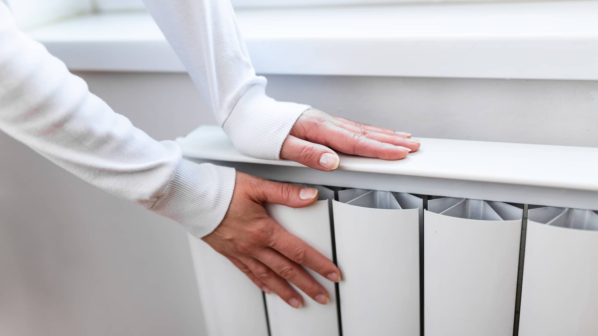 manos de una mujer calentandose en un radiador ya que paga una de las tarifas 3-2 de iberdrola