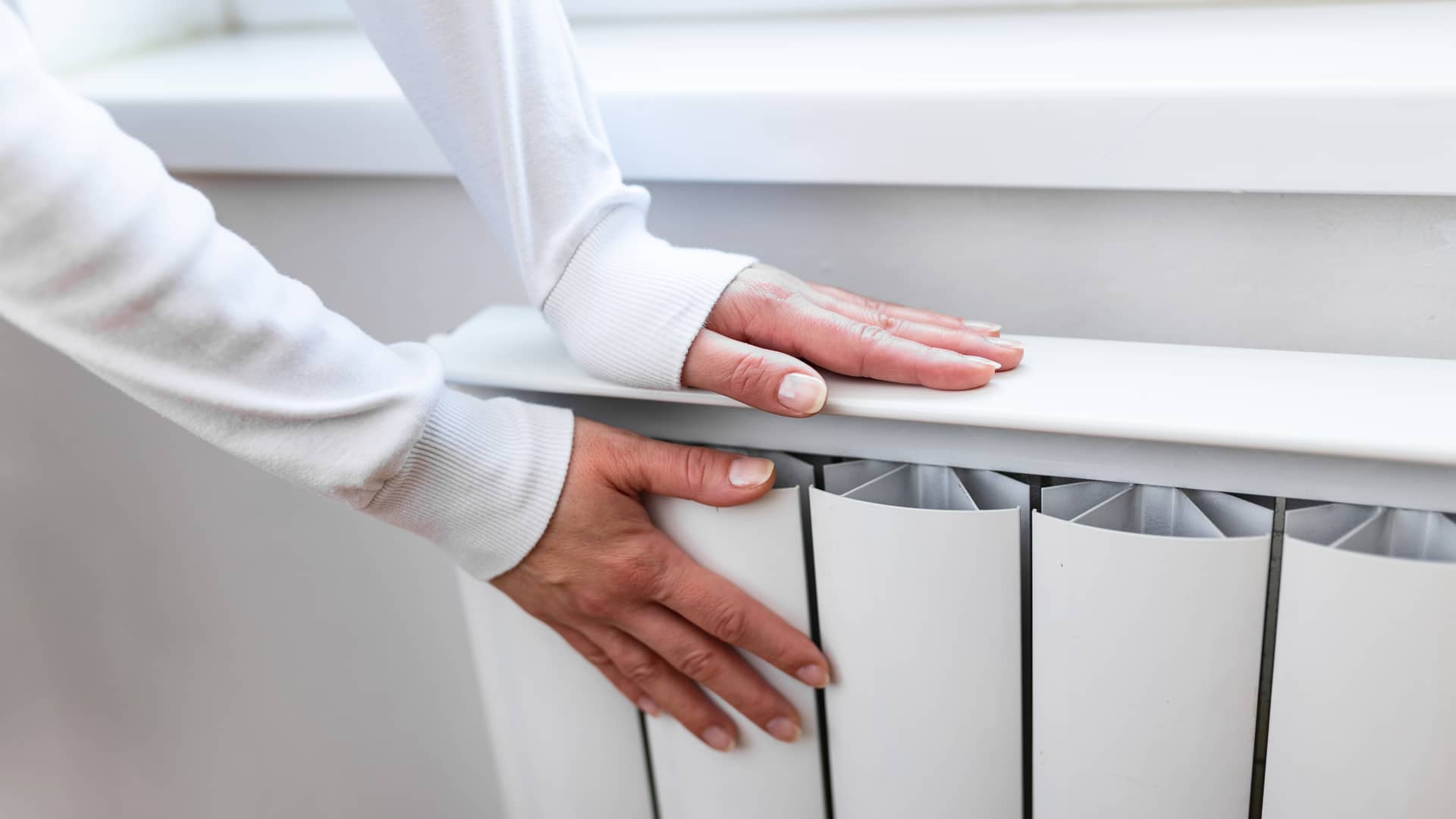 manos de una mujer calentandose en un radiador ya que paga una de las tarifas 3-2 de iberdrola manos de una mujer calentandose en un radiador ya que paga una de las tarifas 3-2 de iberdrola