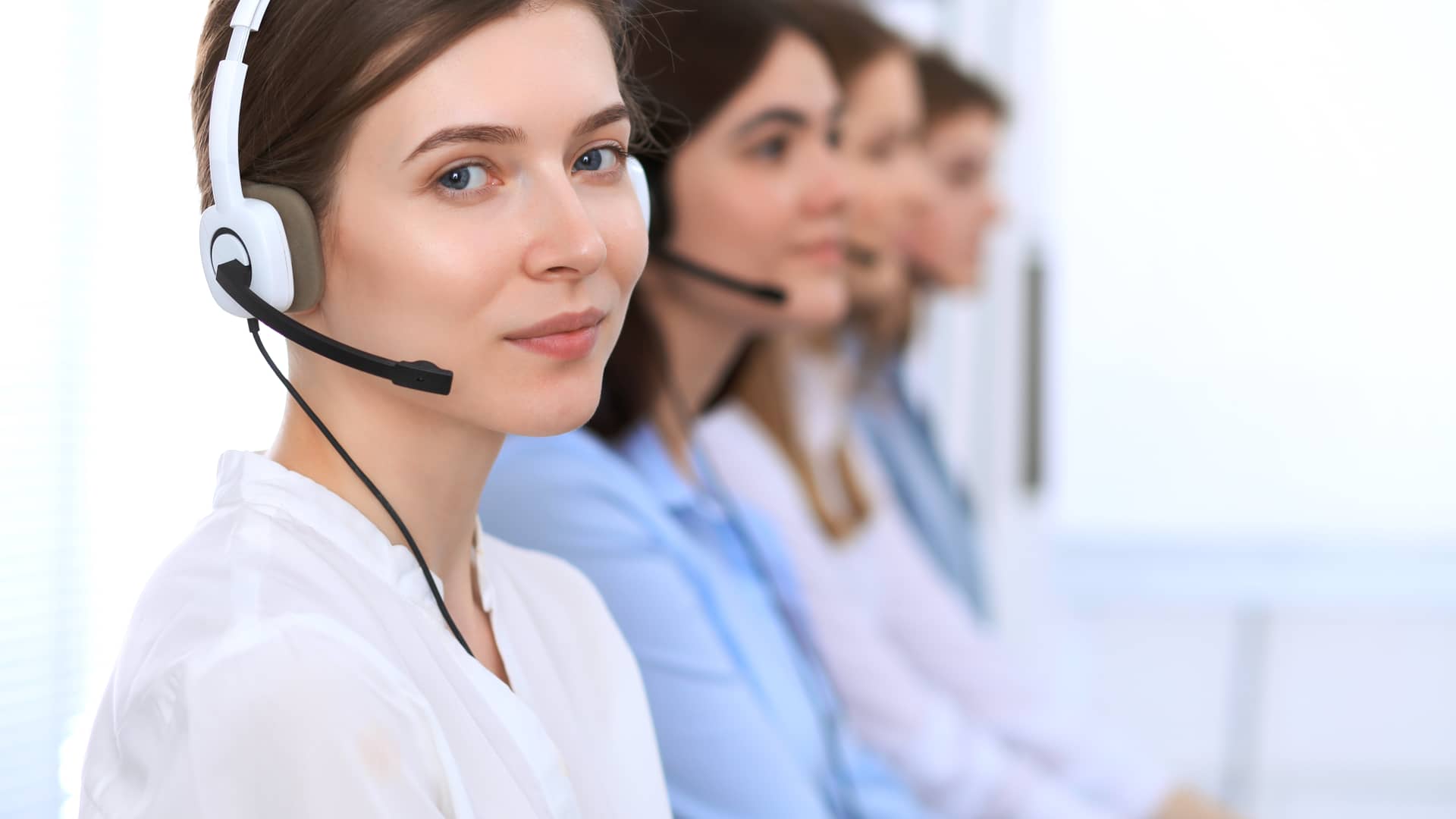 Mujer de atención al cliente de imagina energía mira a cámara en un descanso entre llamadas al teléfono de clientes Mujer de atención al cliente de imagina energía mira a cámara en un descanso entre llamadas al teléfono de clientes