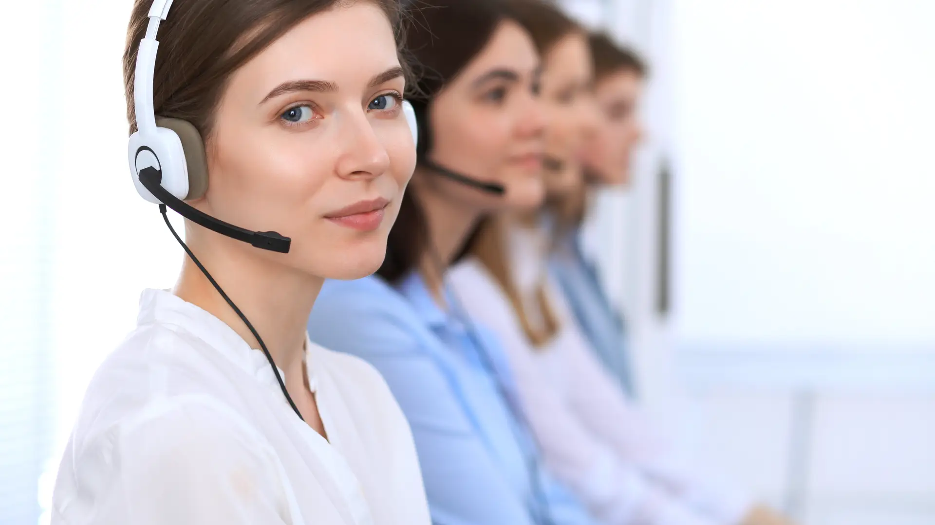 Mujer de atención al cliente de imagina energía mira a cámara en un descanso entre llamadas al teléfono de clientes Mujer de atención al cliente de imagina energía mira a cámara en un descanso entre llamadas al teléfono de clientes