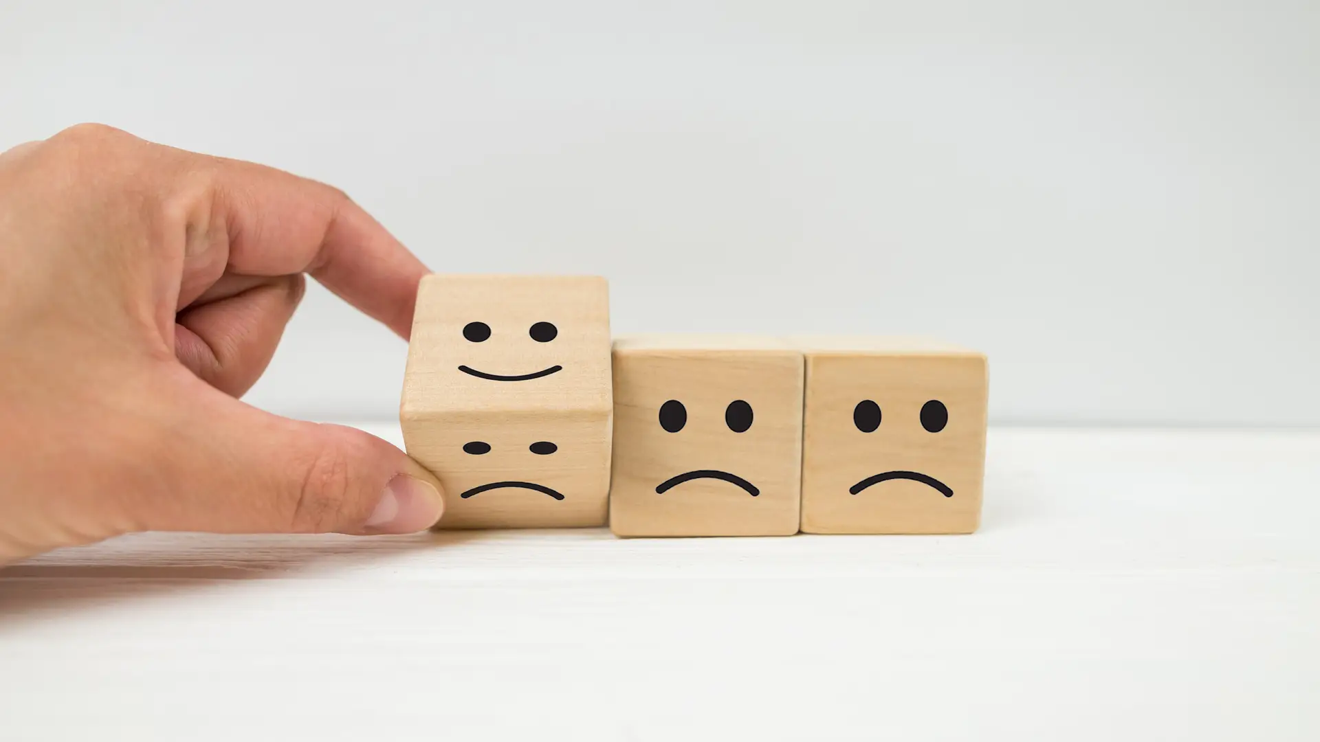 Mano volteando las caras de un dado de triste a contento representa las opiniones de los clientes de logos energía Mano volteando las caras de un dado de triste a contento representa las opiniones de los clientes de logos energía