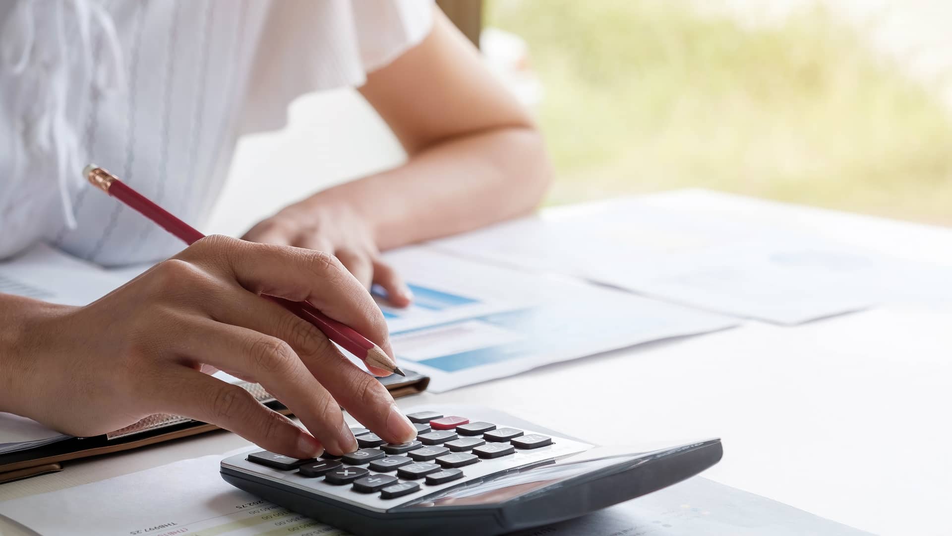 Mujer con calculadora repasando factura de xenera Mujer con calculadora repasando factura de xenera