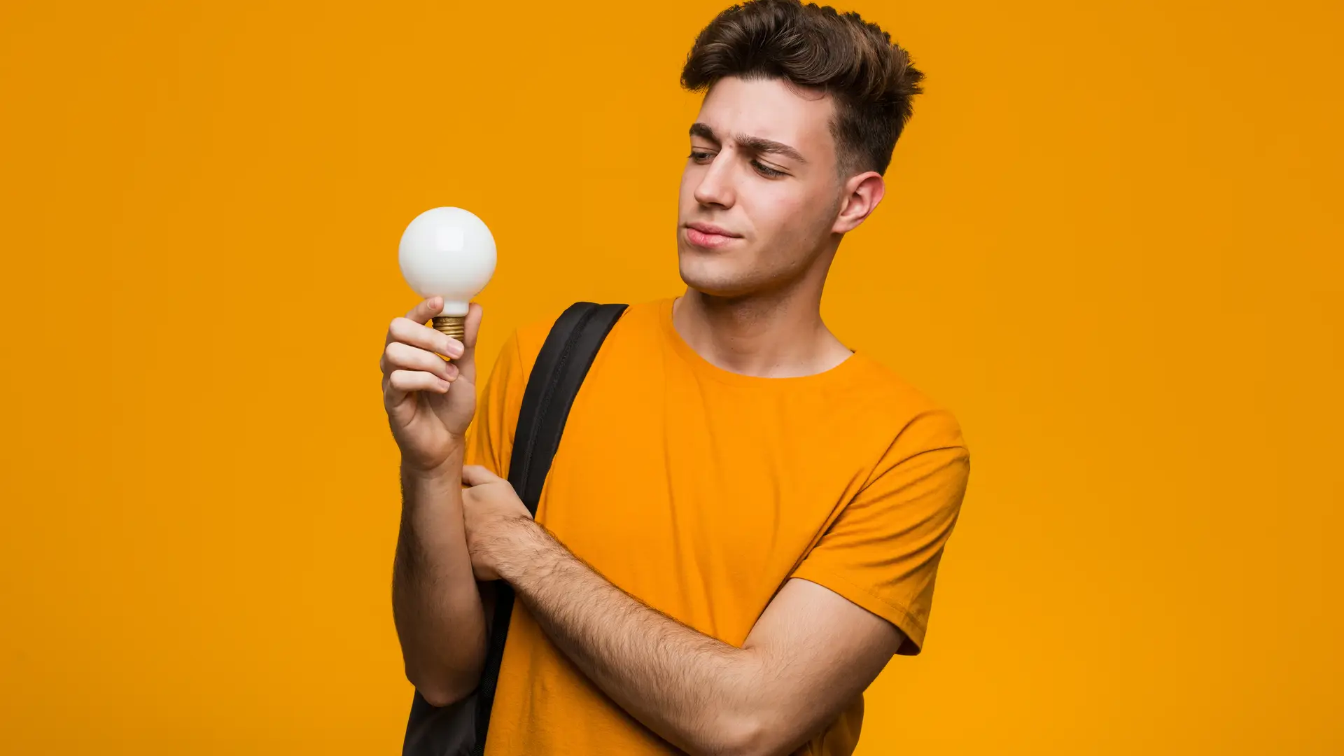 Joven mirando una bombilla mientras se pregunta las diferencias entre kw y el kwh