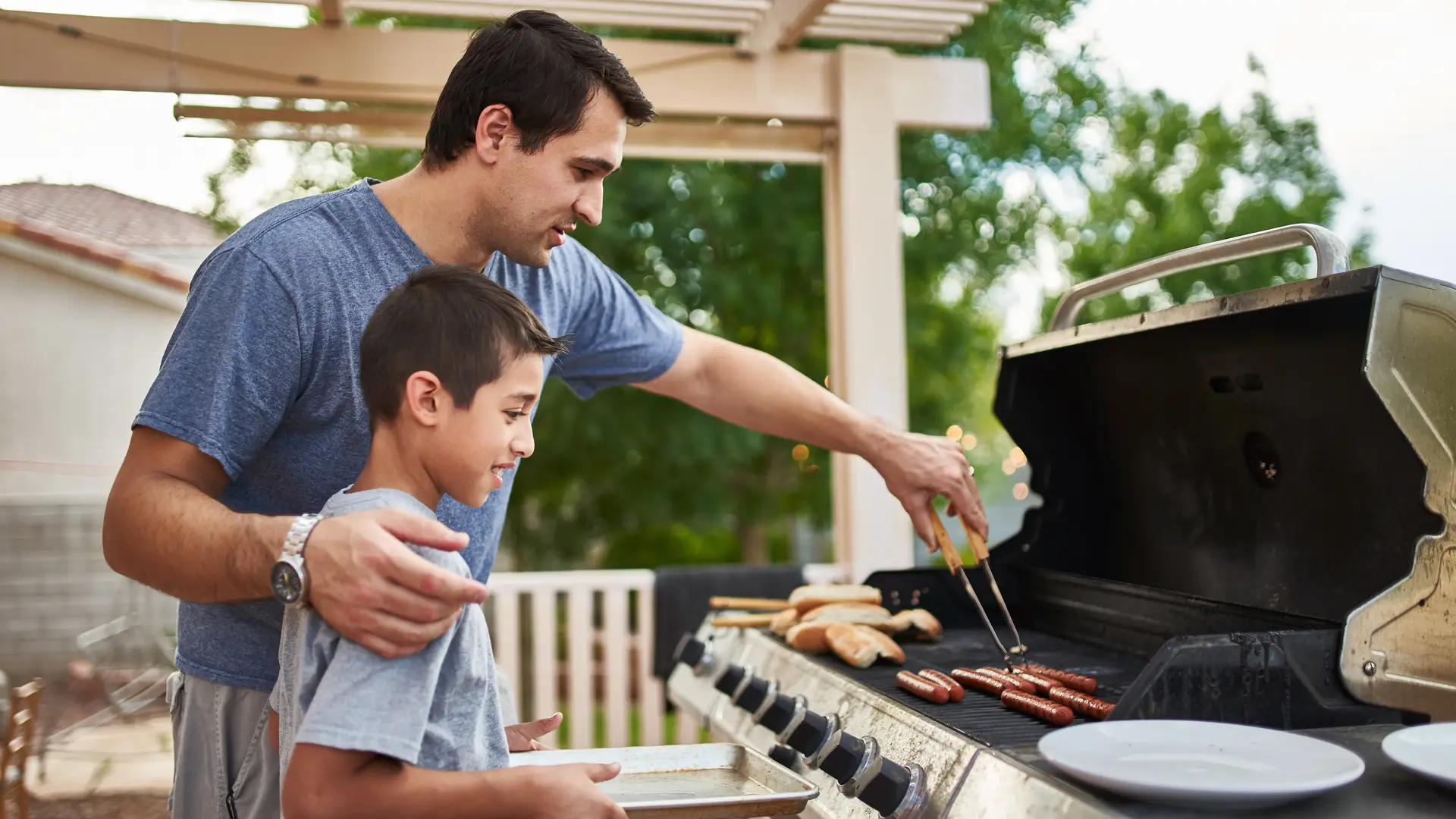 Padre e hijo cocinando en barbacoa con alto consumo de gas Padre e hijo cocinando en barbacoa con alto consumo de gas