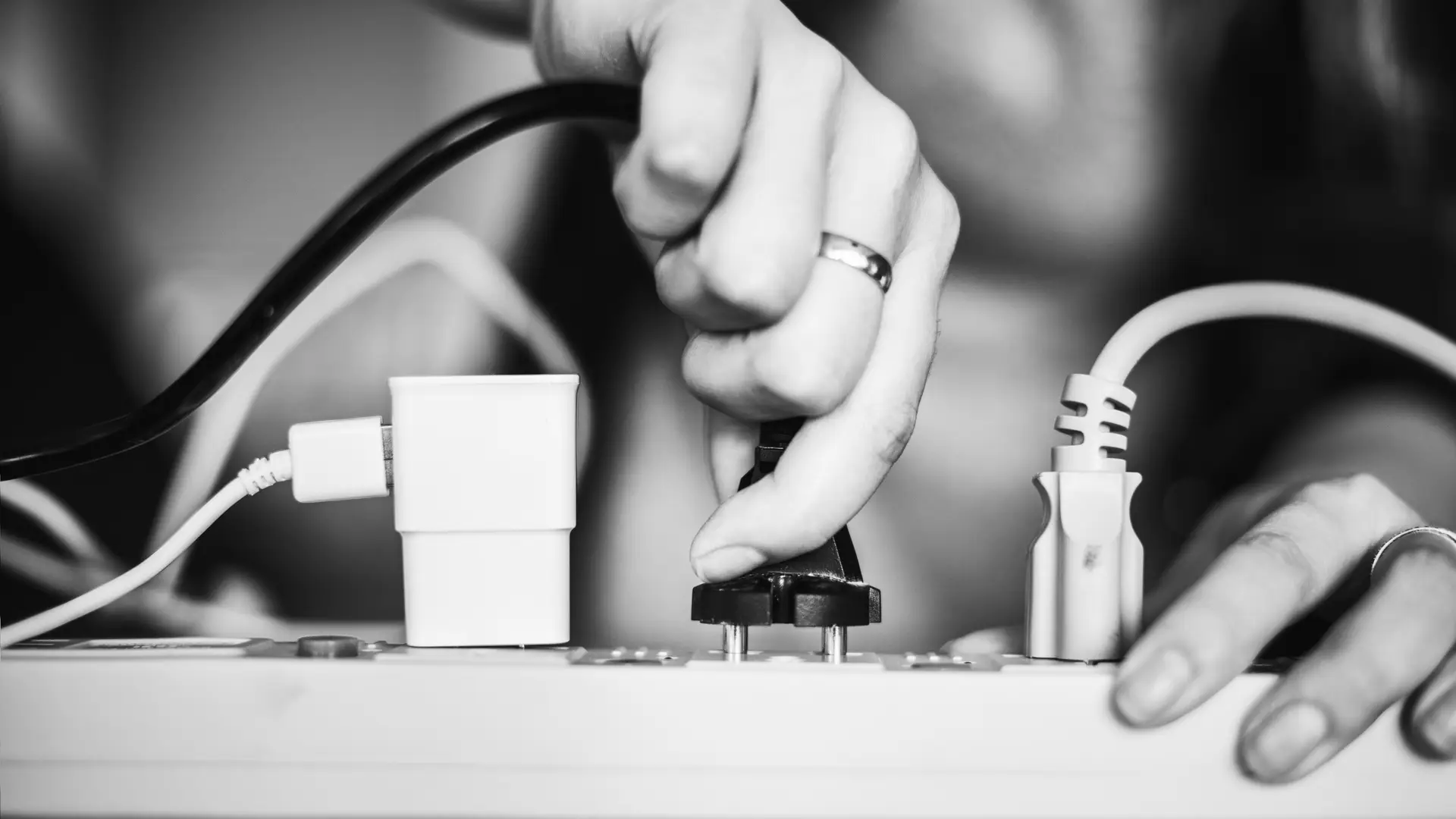 Mano de mujer desenchufando un electrodoméstico ya que ha reducido la potencia eléctrica contratada y no quiere arriesgarse a saltar los plomos
