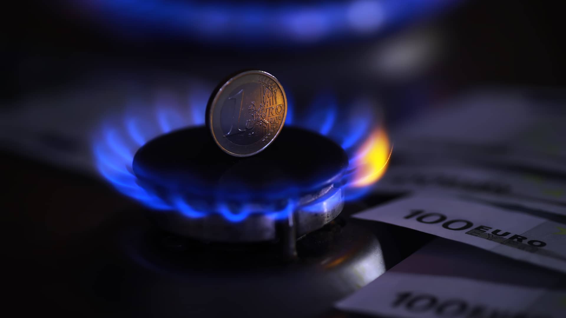 moneda encima de una cocina de gas que representa el tope de precio de luz y gas