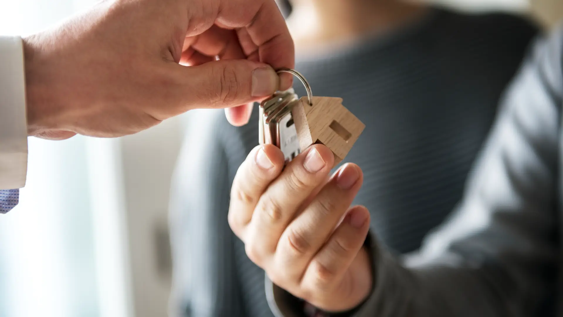 Hombre dando las llaves de su nueva vivienda a pareja la cual tendrá que pagar el impuesto de transmisiones patrimoniales Hombre dando las llaves de su nueva vivienda a pareja la cual tendrá que pagar el impuesto de transmisiones patrimoniales