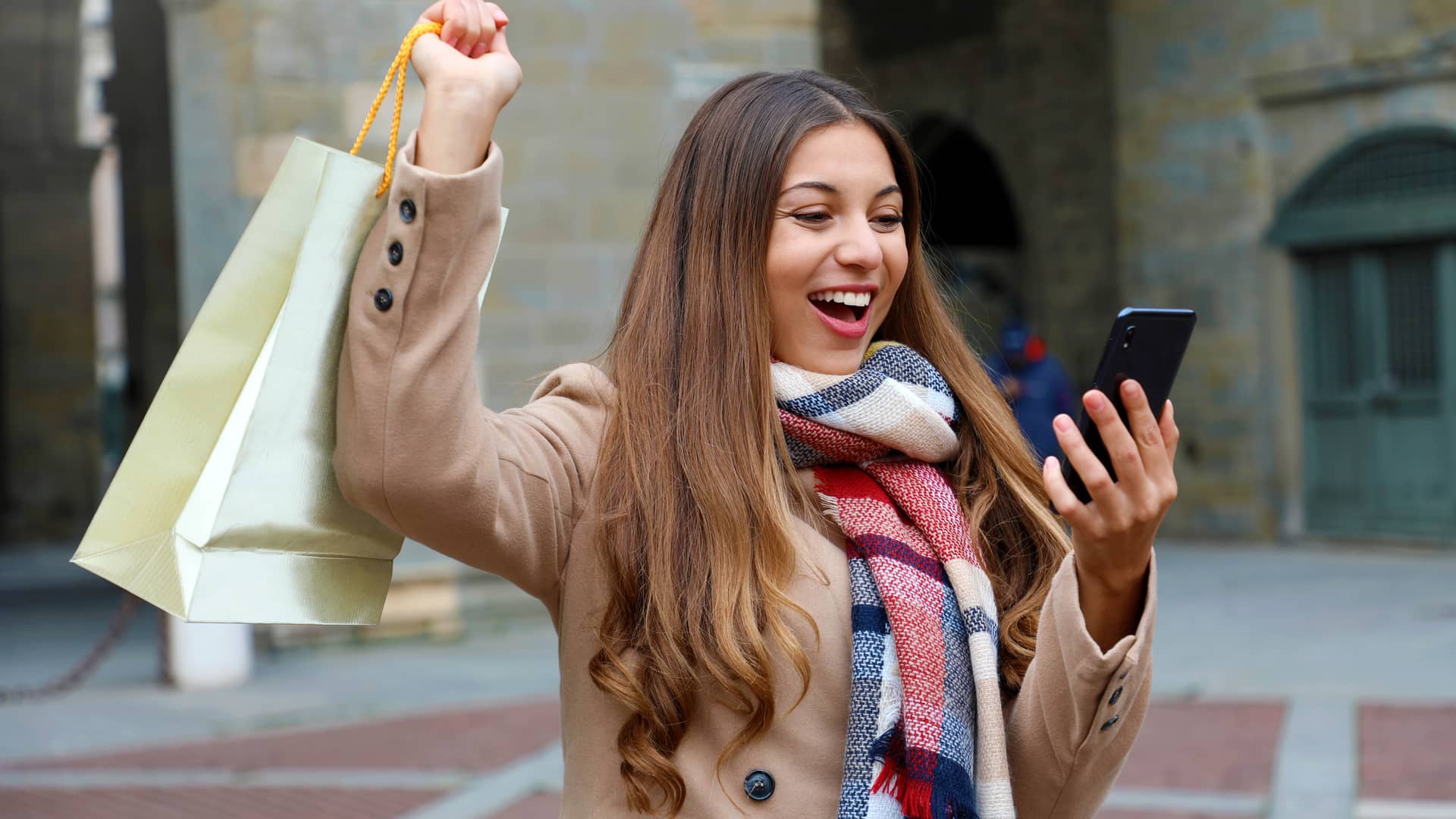 Mujer sonrie tras recibir dinero en su movil mediante hal cash para seguir de compras