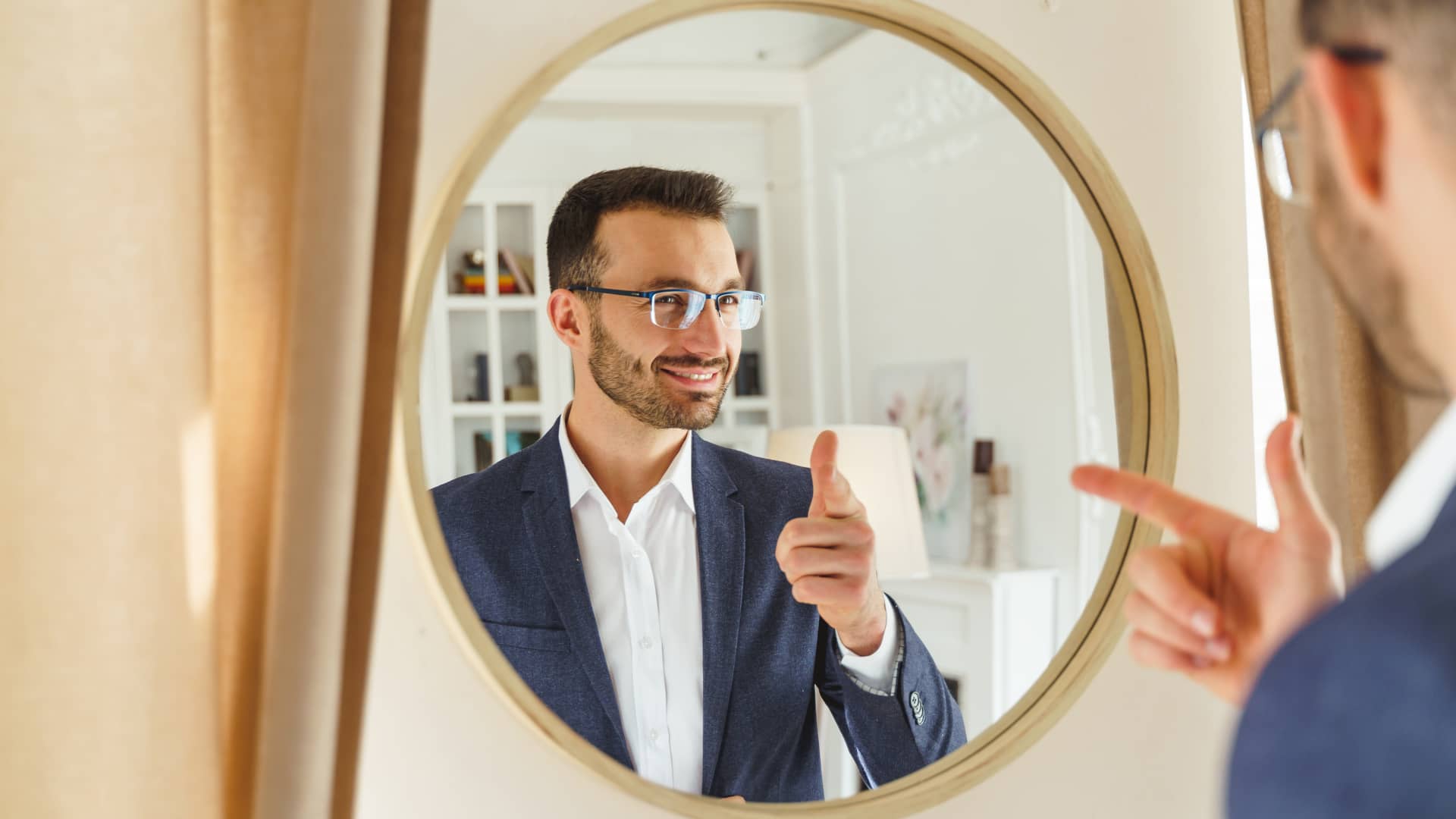 Hombre sonriente mirandose en el espejo tras ver su cuenta Hombre sonriente mirandose en el espejo tras ver su cuenta