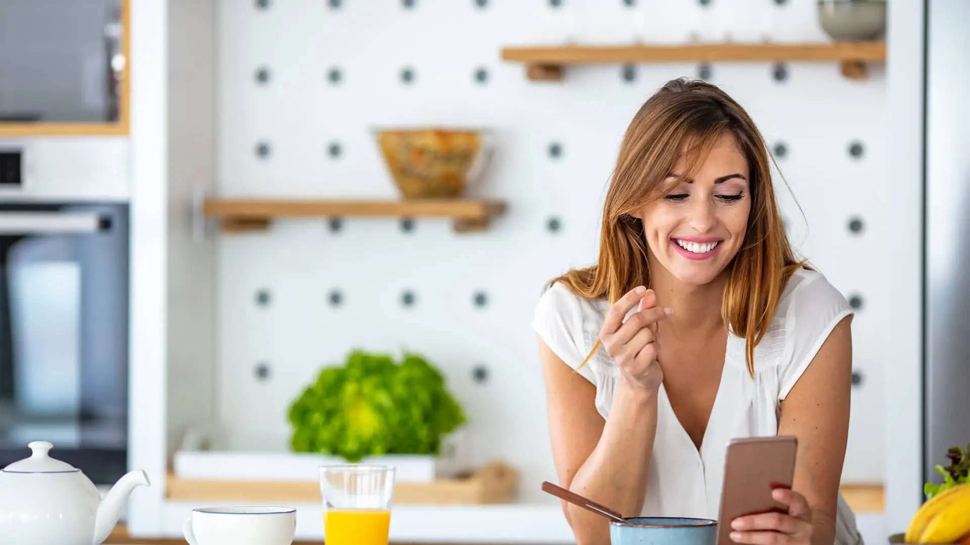 Joven feliz viendo sus cuentas online sín comisiones en su smartphone Joven feliz viendo sus cuentas online sín comisiones en su smartphone