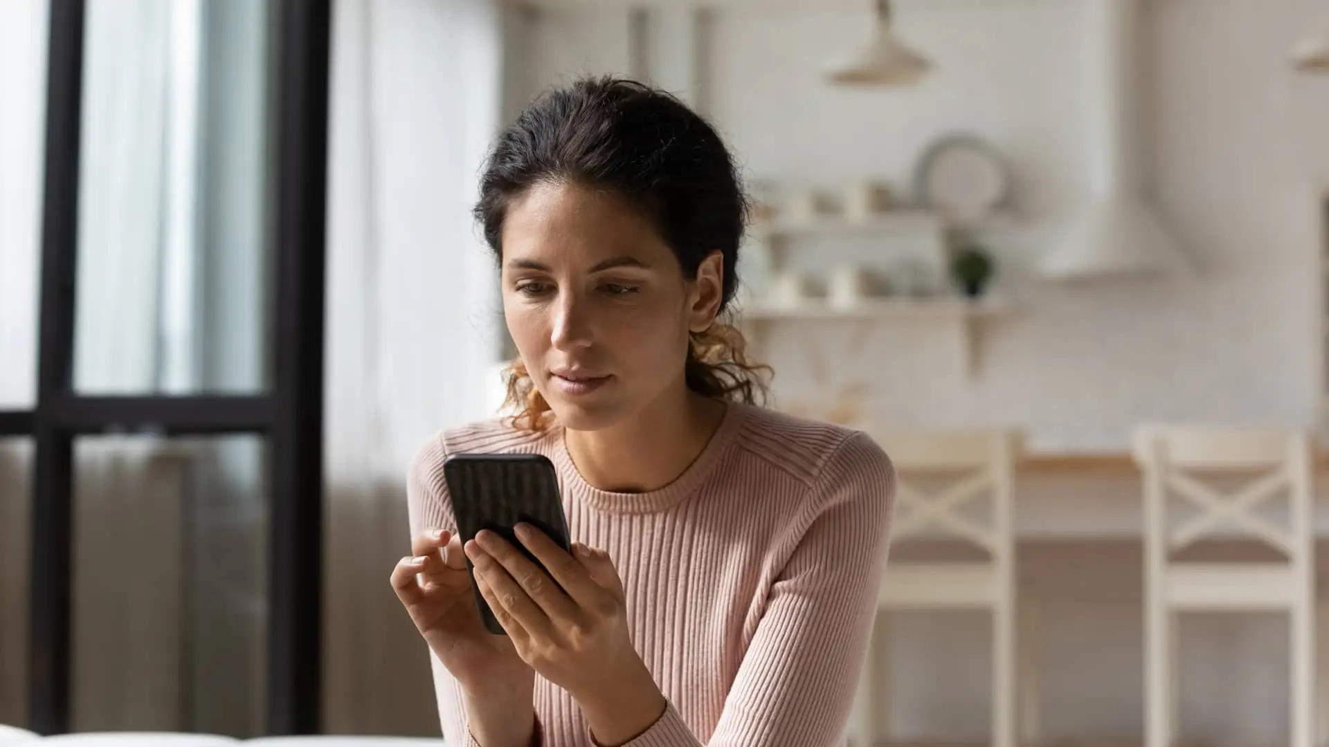 Mujer buscando en su smartphone como dar de baja cuenta de fallecido