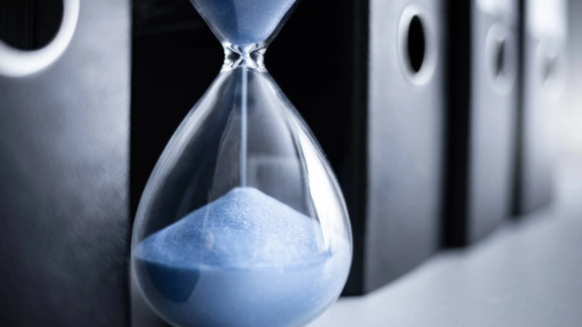 Reloj de arena entre carpetas de papeles representa el tiempo que queda en un depósito estructurado
