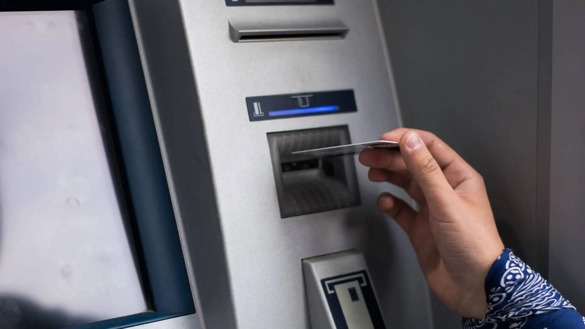 Joven introduciendo tarjeta de crédito en cajero automático de oficinas de cajasiete Joven introduciendo tarjeta de crédito en cajero automático de oficinas de cajasiete