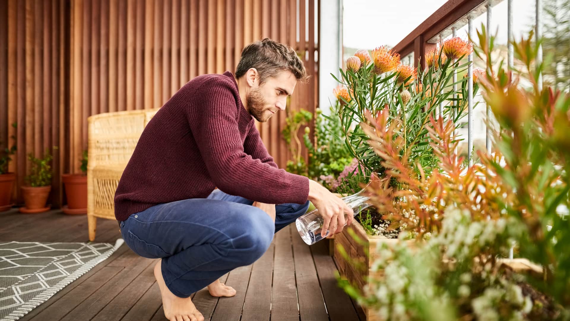 Joven regando plantas de su nuevo hogar comprado a inmobiliaria de cajasur