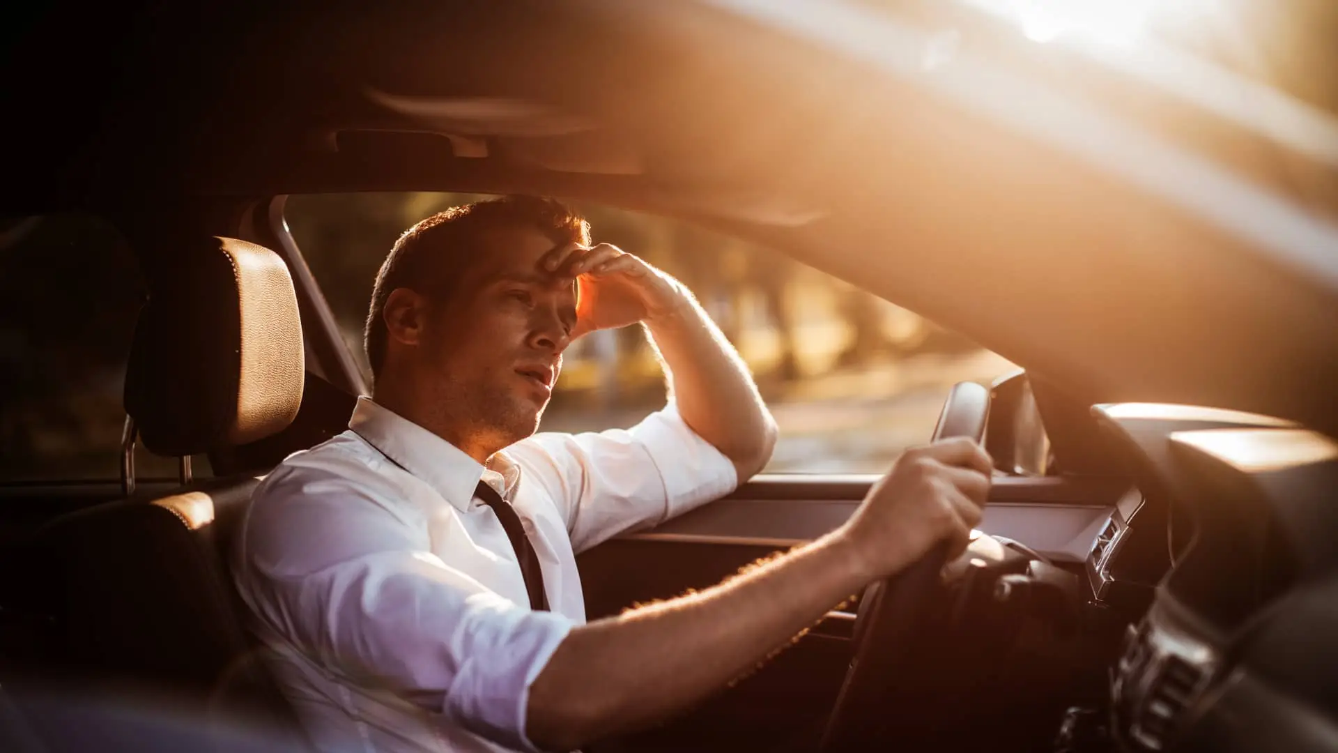 Joven cansado conduciendo su coche asegurado con deutsche bank Joven cansado conduciendo su coche asegurado con deutsche bank