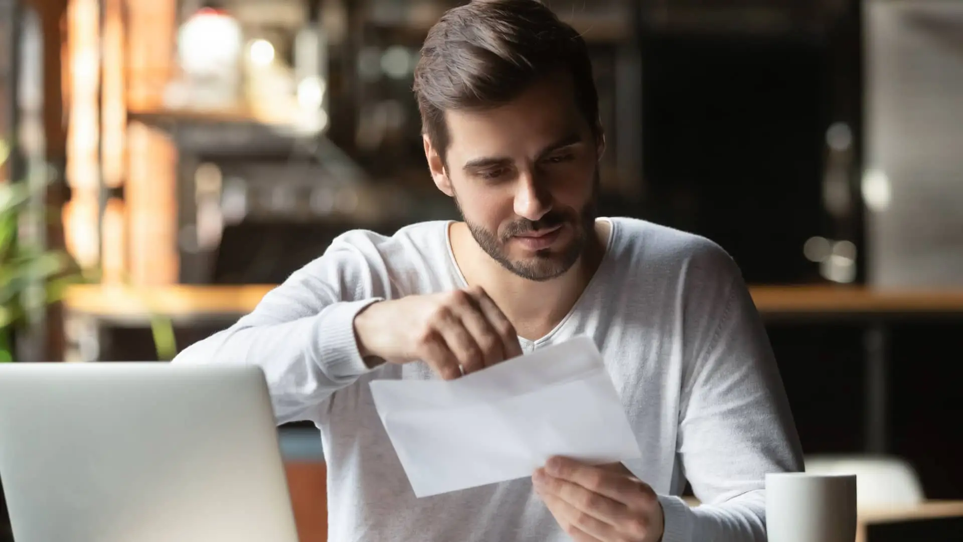 Hombre abriendo carta de domiciliación de nomina Hombre abriendo carta de domiciliación de nomina