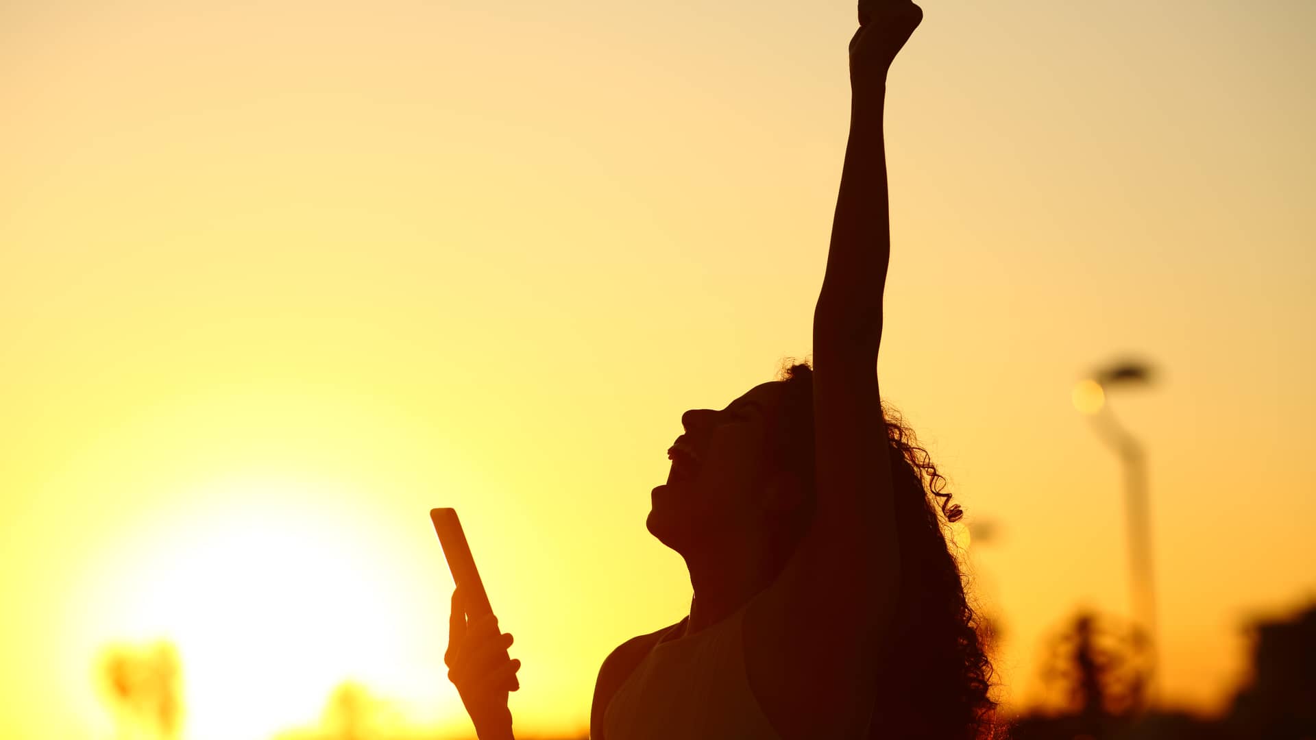 Mujer al atardecer con su smartphone celebrando que le han concedido un prestamo ing Mujer al atardecer con su smartphone celebrando que le han concedido un prestamo ing