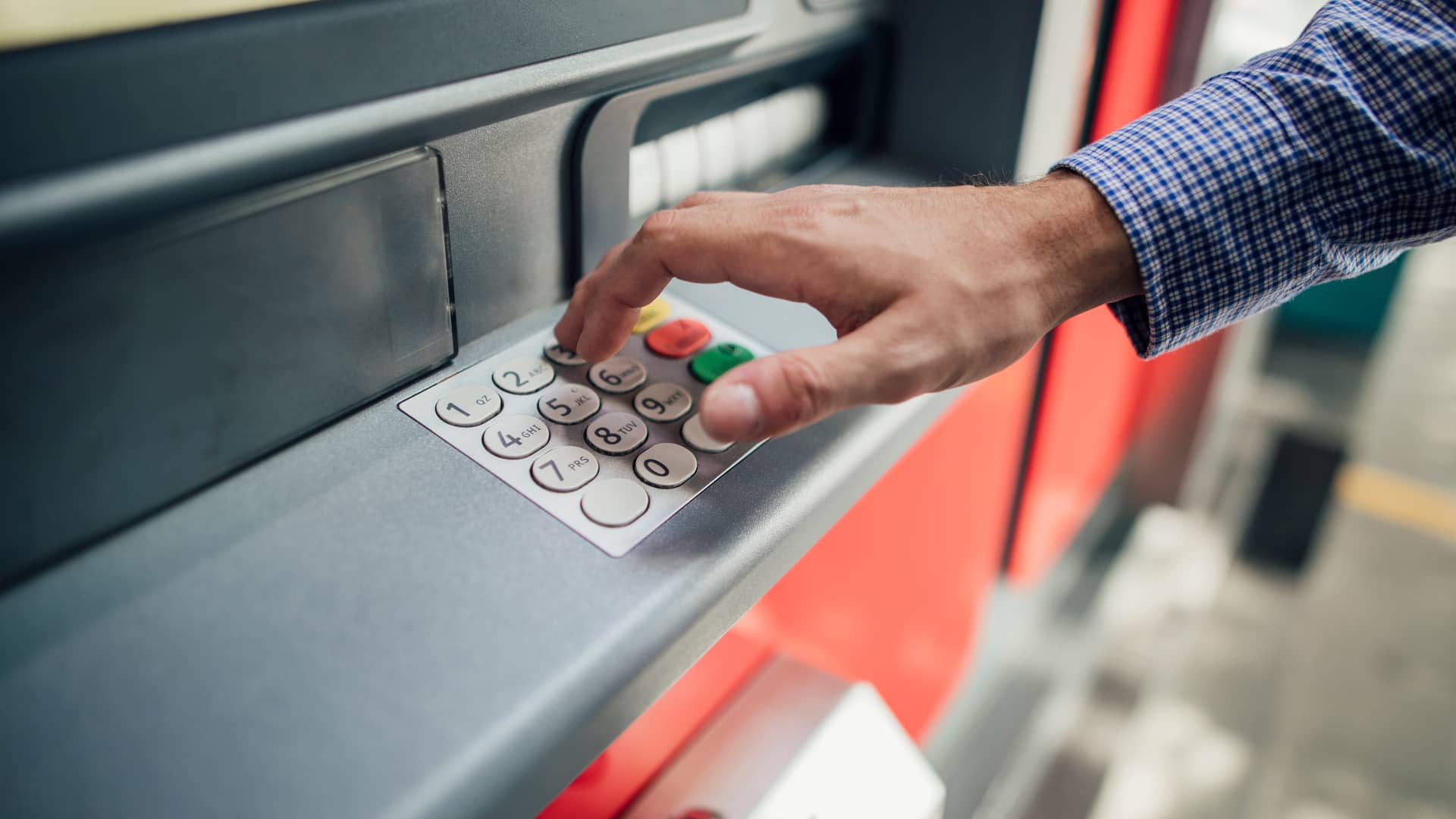 Hombre marcando número secreto en cajero automático para sacar dinero sín tarjeta Hombre marcando número secreto en cajero automático para sacar dinero sín tarjeta