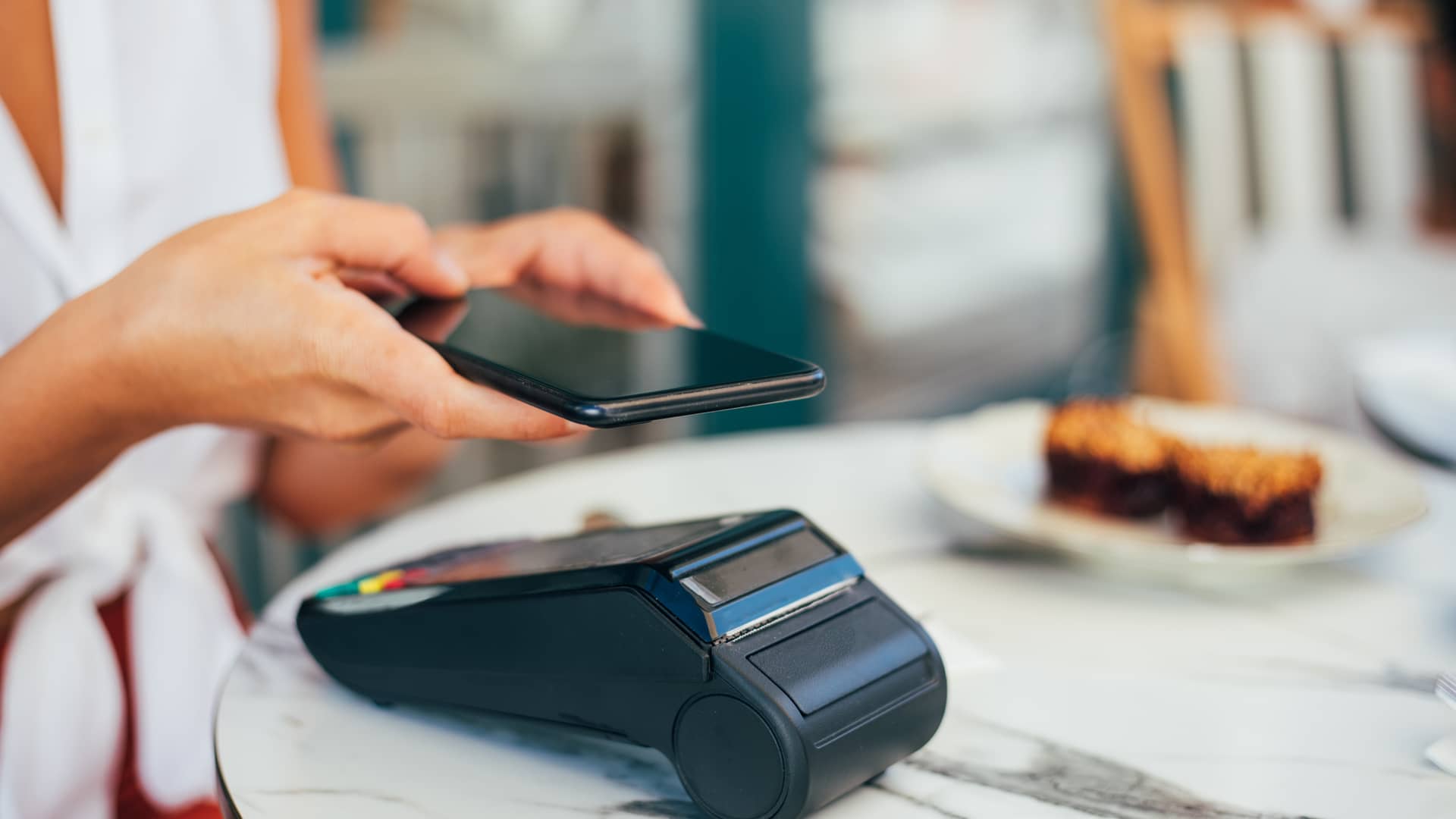 Mujer pagando con su movil en tpv Mujer pagando con su movil en tpv
