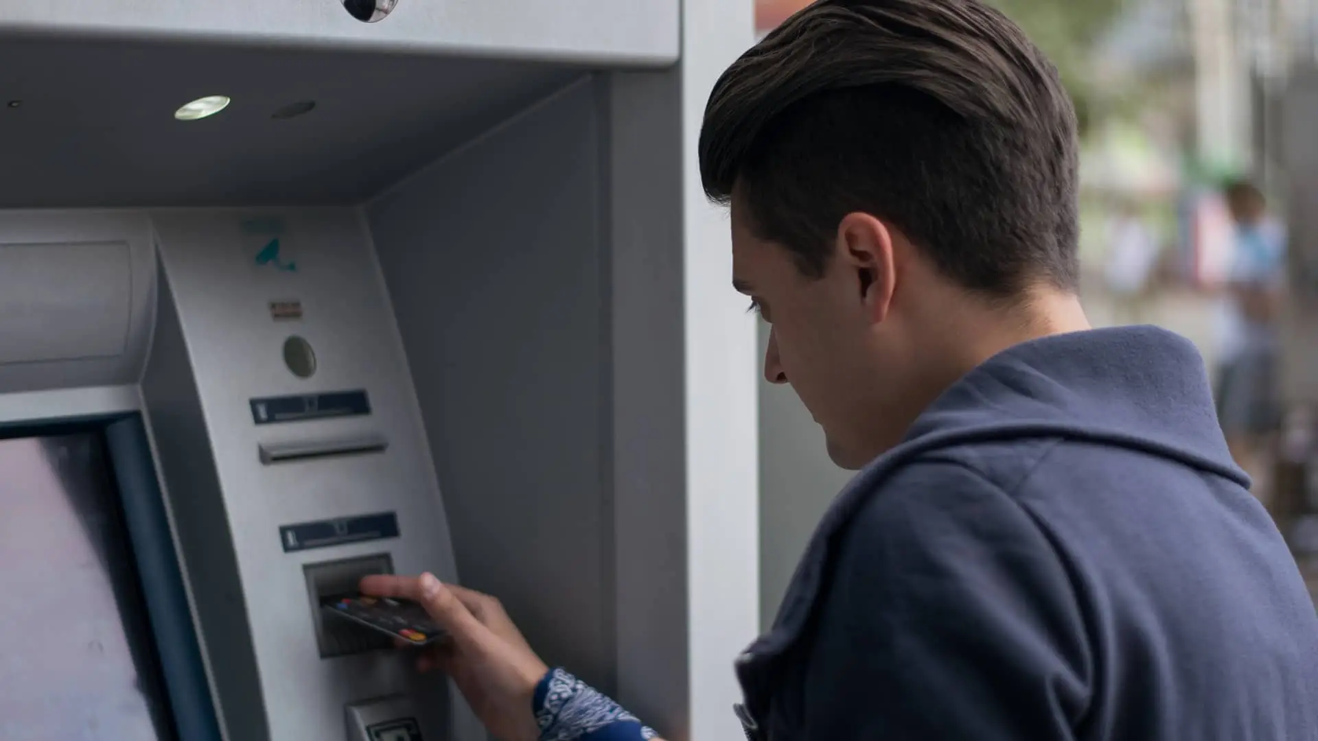 Hombre introduciendo tarjeta de crédito en cajero de oficina mediolanum