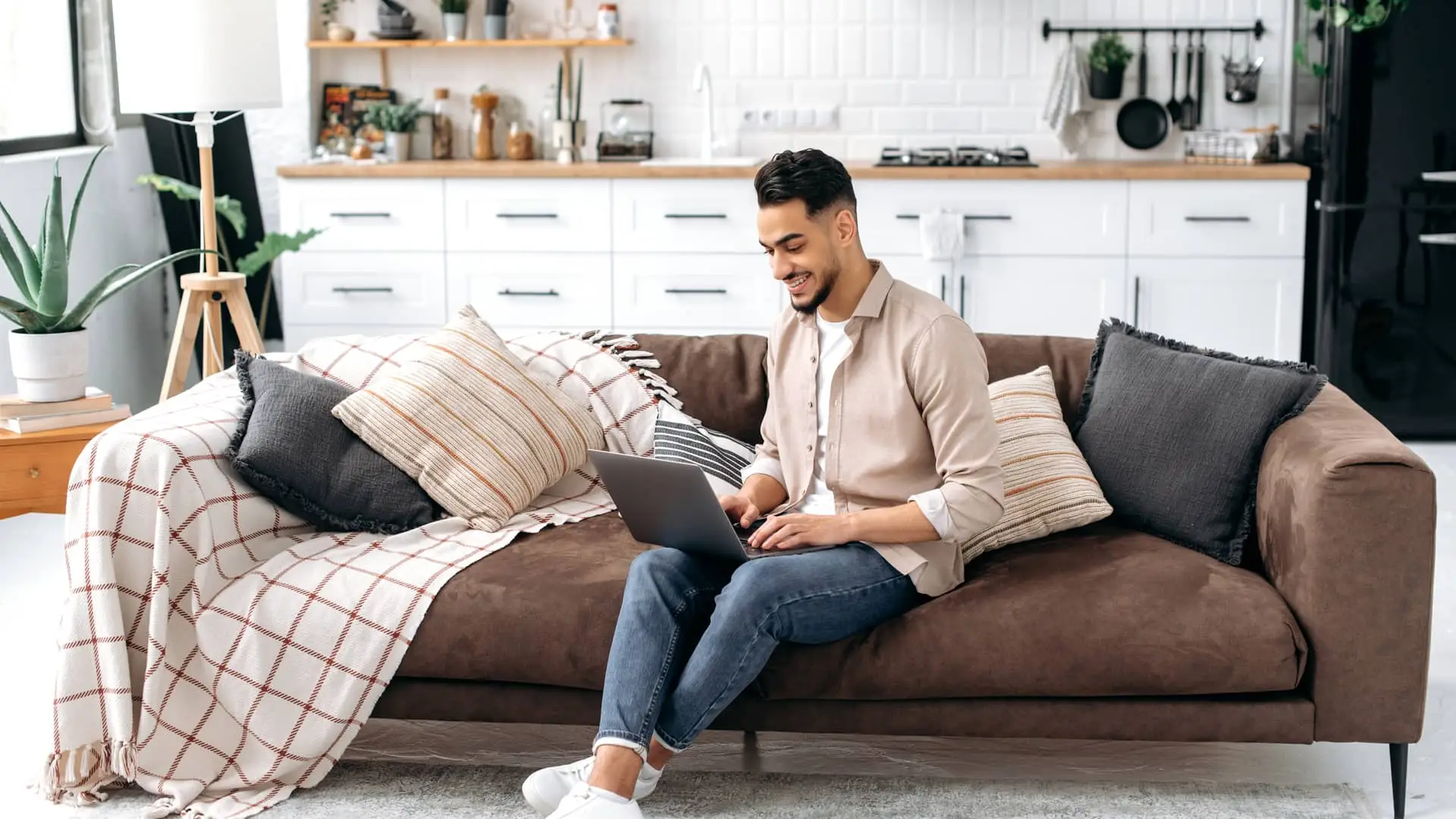 Un chico con el ordenador en el sofa haciendo los tramites para domiciliar la nomina con la entidad Openbank Un chico con el ordenador en el sofa haciendo los tramites para domiciliar la nomina con la entidad Openbank