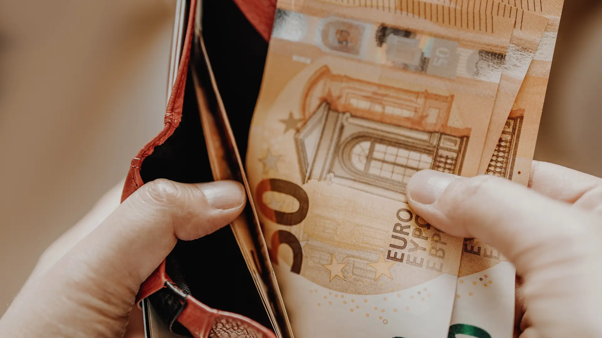 Una persona sacando billetes de 50 euros de su cartera gracias a uno de los prestamos de la entidad revolut