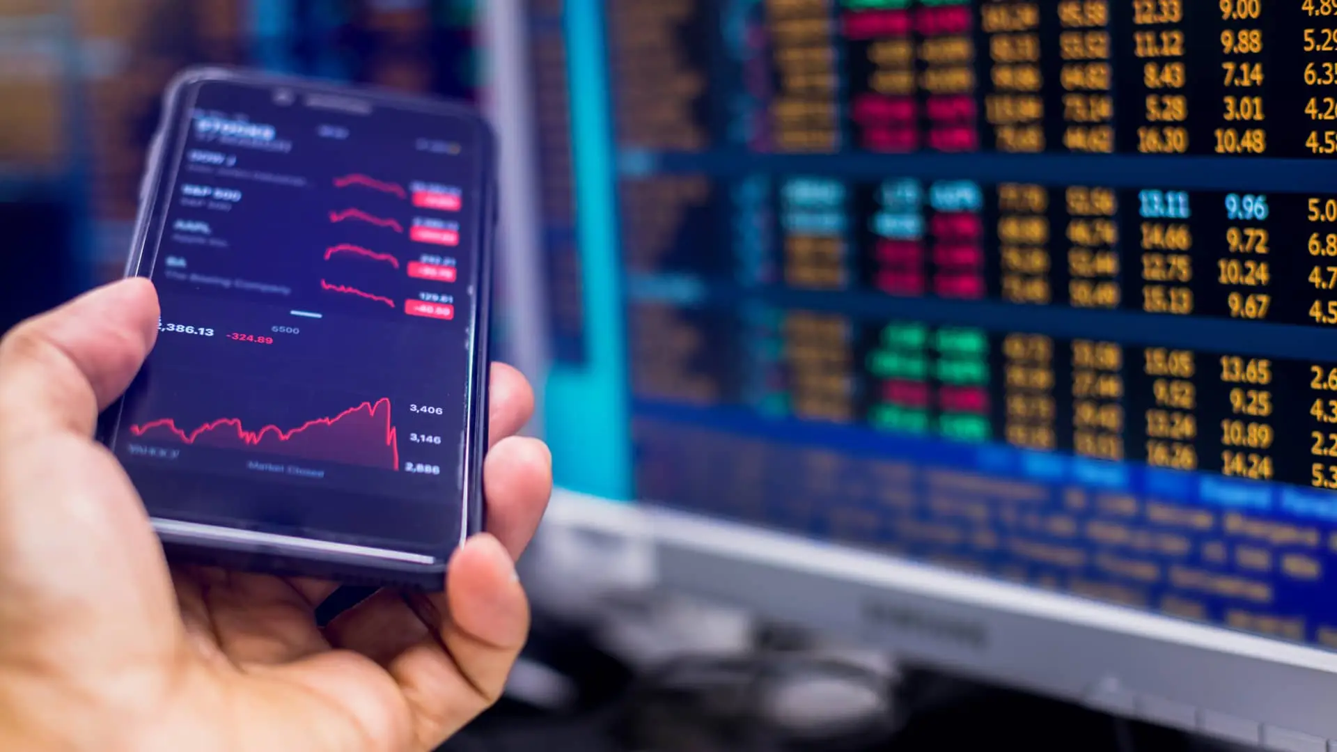 Broker con su smartphone y monitores observando datos bursátiles Broker con su smartphone y monitores observando datos bursátiles