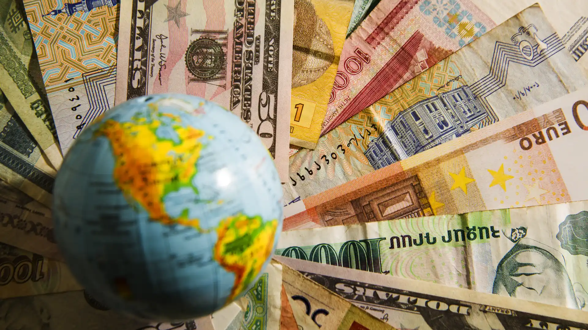 Bola del mundo sobre billetes que hacen referencia al modeo 720 de hacienda sobre dinero en el extranjero con vivid money