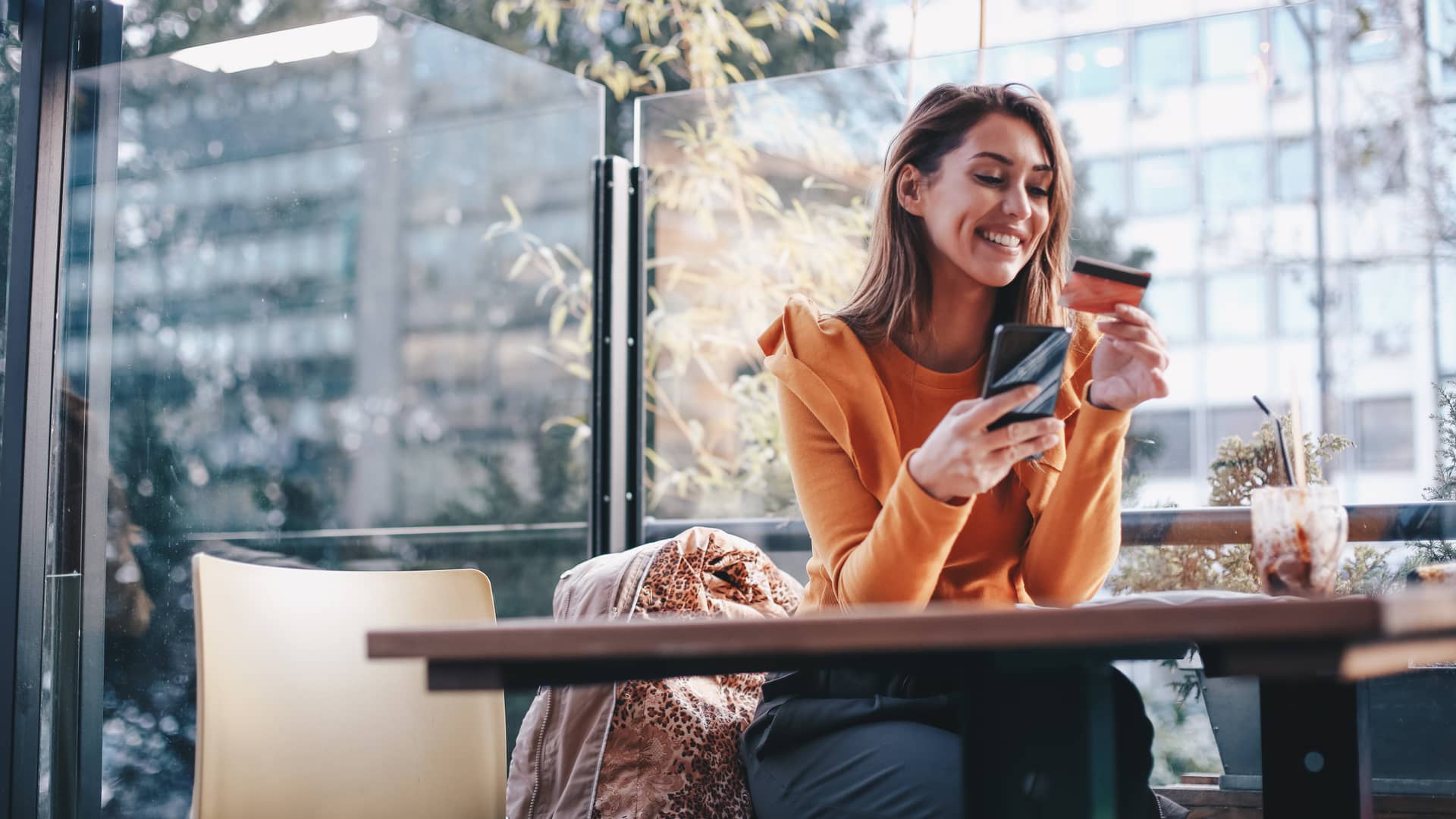 Mujer usando tarjeta de crédito de wise para realizar una compra online con su móvil