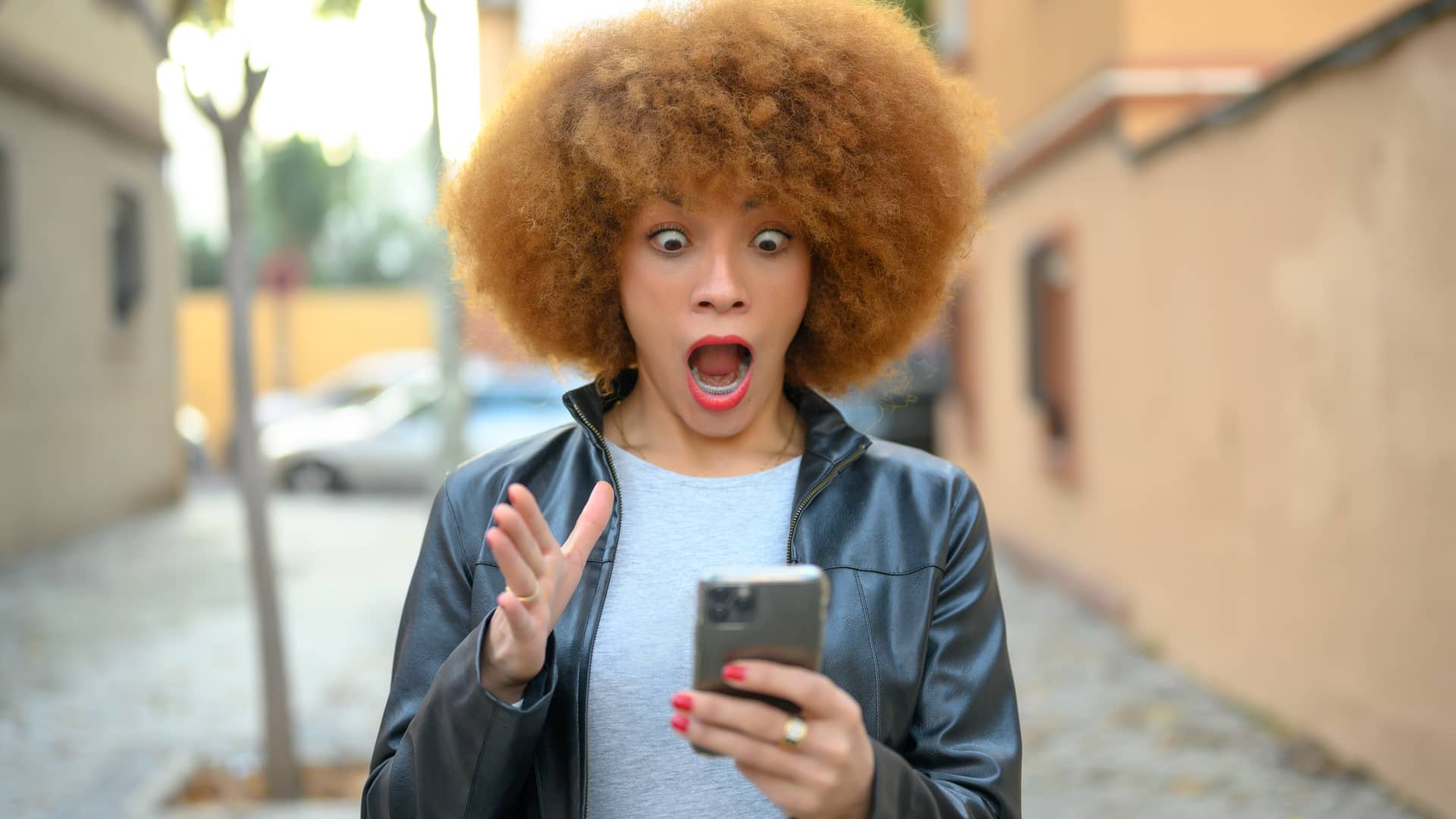 Mujer con cara de sorprendida al recibir en su smartphone un aviso de robo en su inversión Mujer con cara de sorprendida al recibir en su smartphone un aviso de robo en su inversión