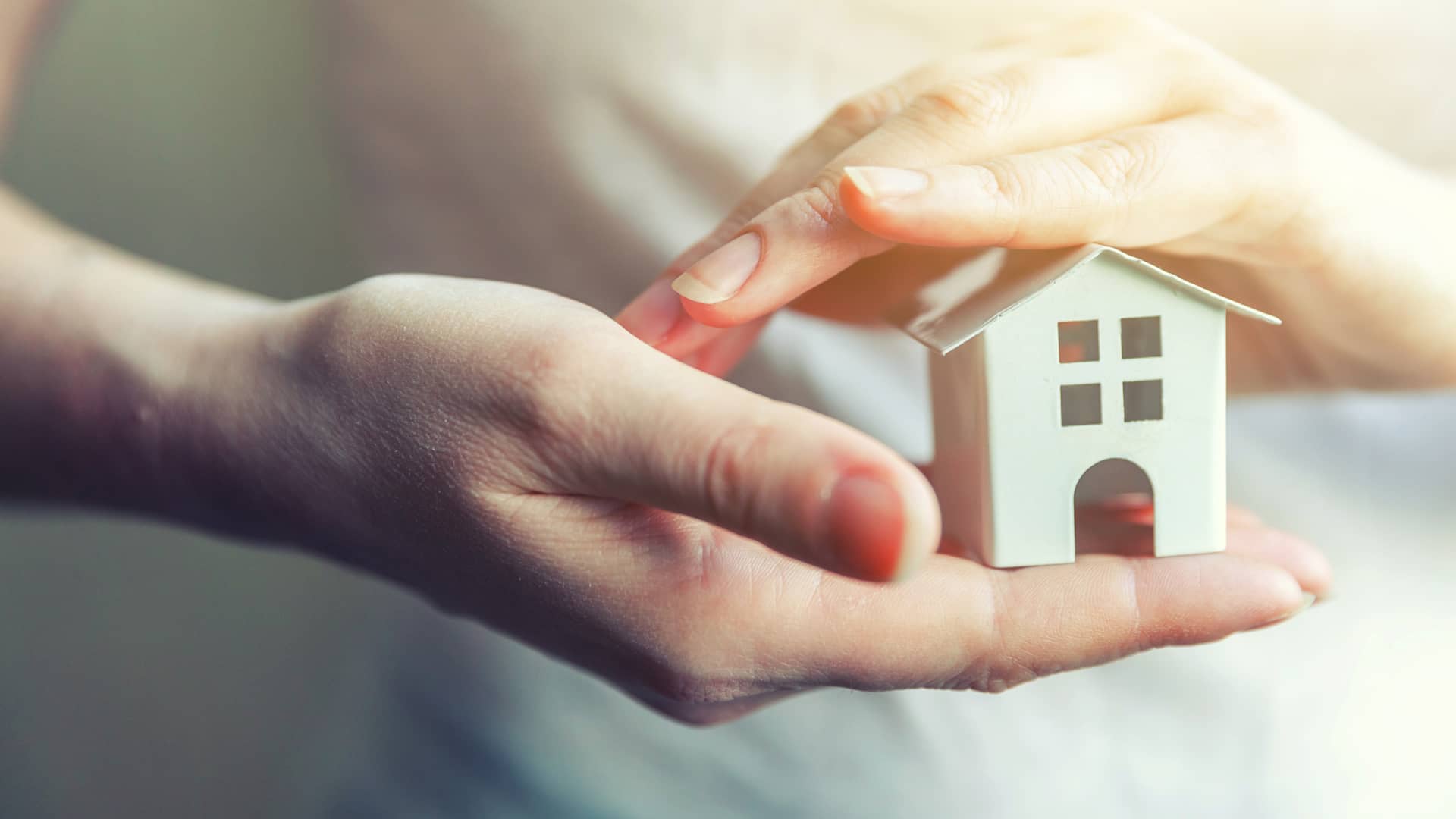 Manos sosteniendo una pequeña casita de juguete representa la tranquilidad de un cliente que cuenta con una hipoteca bonificada Manos sosteniendo una pequeña casita de juguete representa la tranquilidad de un cliente que cuenta con una hipoteca bonificada
