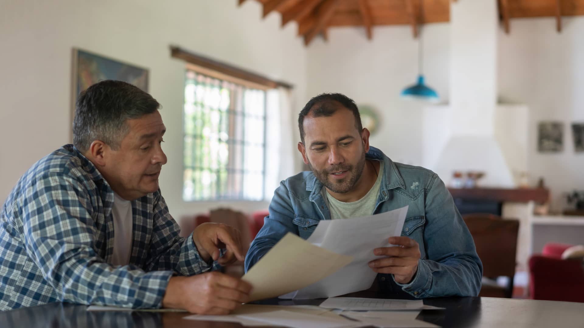 Hombre explicandole a su padre los detalles de la hipoteca de la que necesita que sea su aval para conseguirla