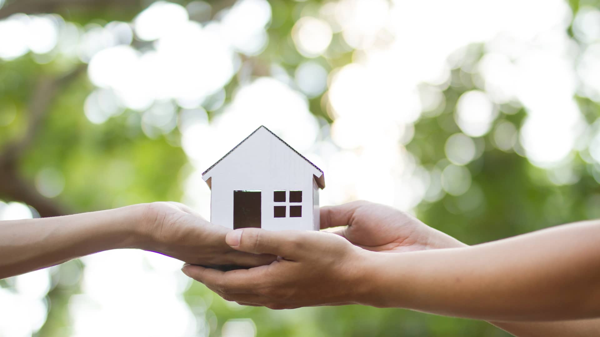 Una persona le entrega a otra una casita símbolizando que ha conseguido su casa fácilmente gracias a una hipoteca rápida Una persona le entrega a otra una casita símbolizando que ha conseguido su casa fácilmente gracias a una hipoteca rápida