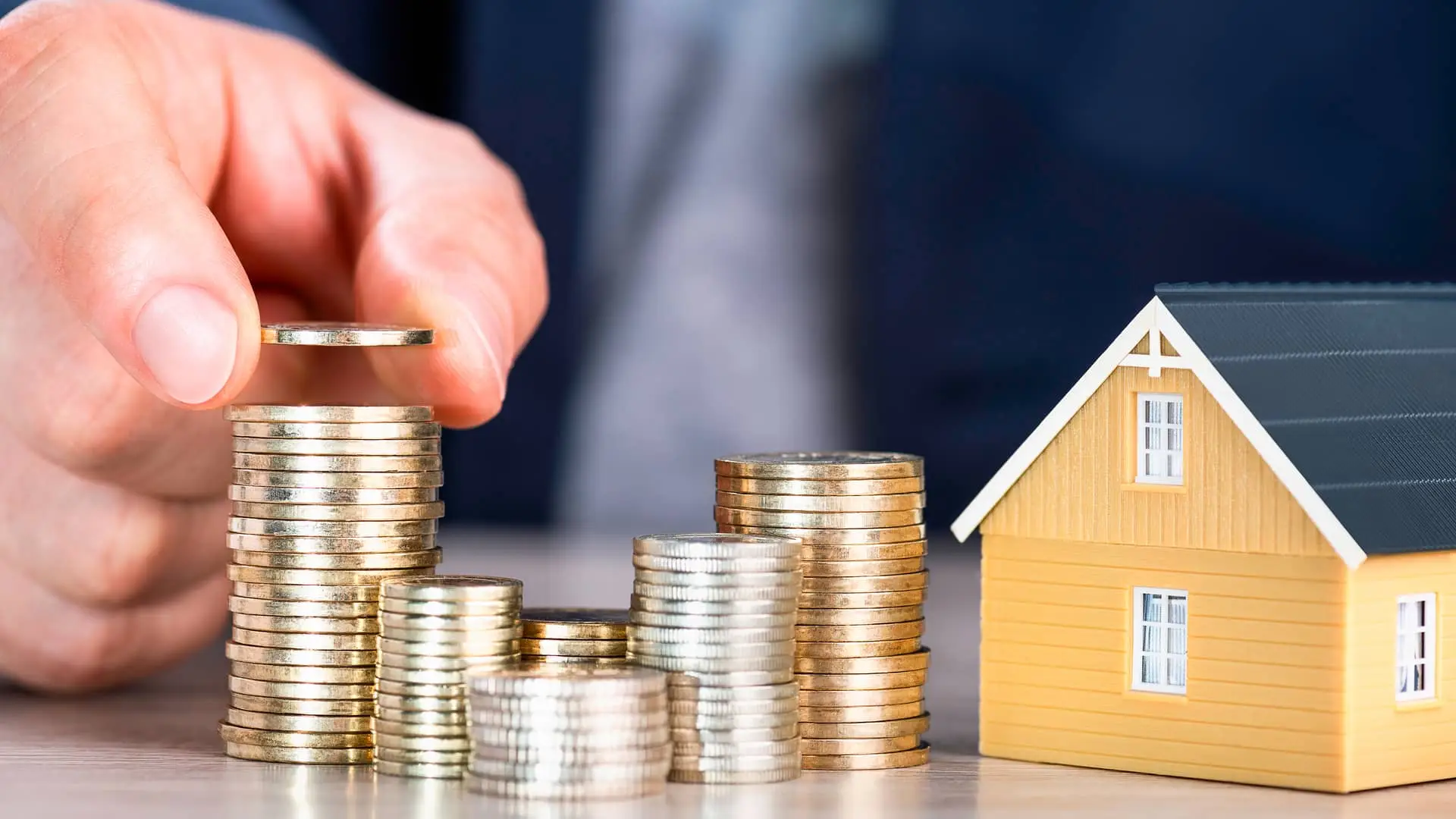 Replica de casa y monton de monedas simboliza hipotecas baratas