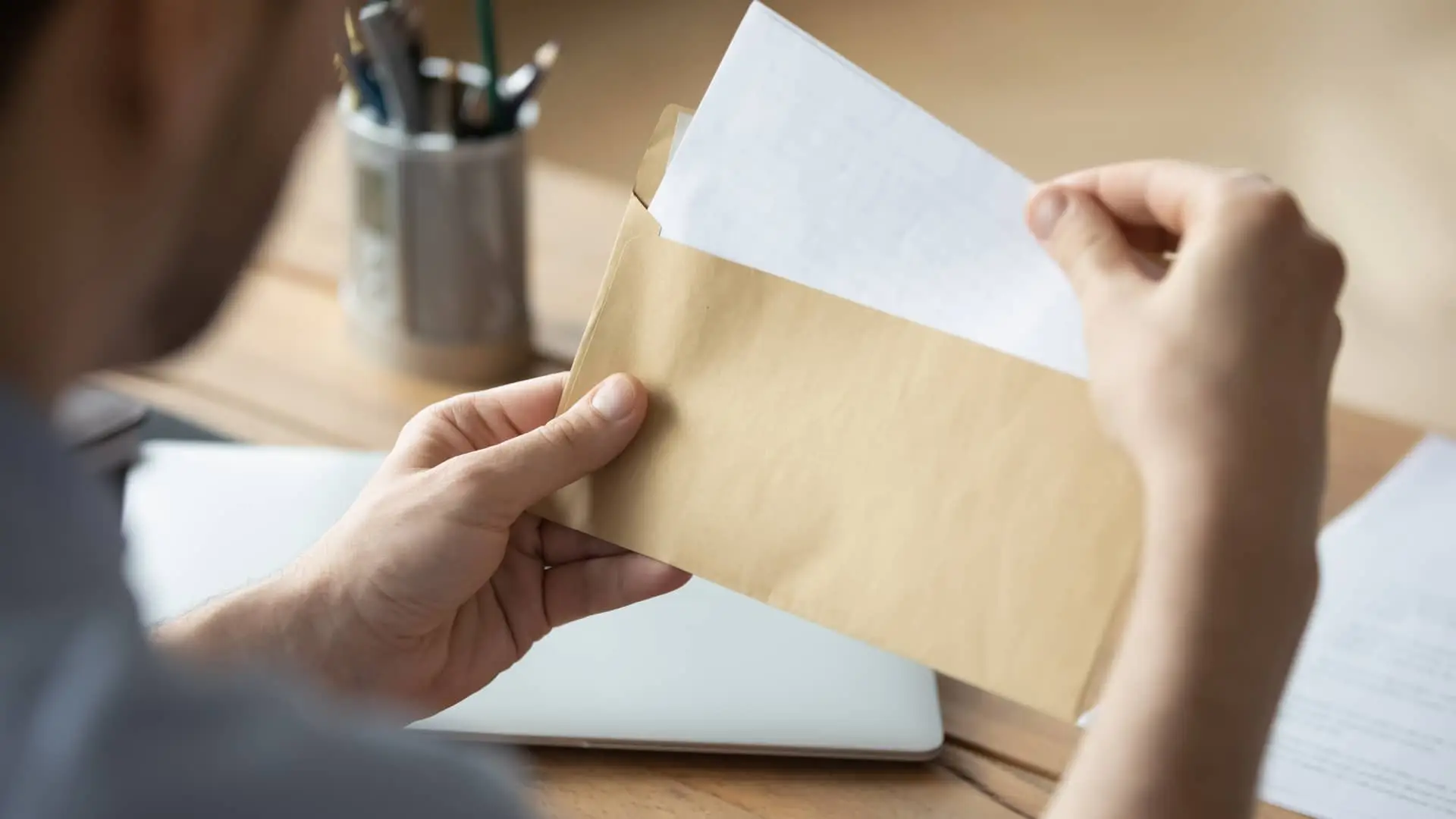 Chico cerrando un sobre de carta con los papeles para reclamar los gastos de su hipoteca con kutxabank Chico cerrando un sobre de carta con los papeles para reclamar los gastos de su hipoteca con kutxabank