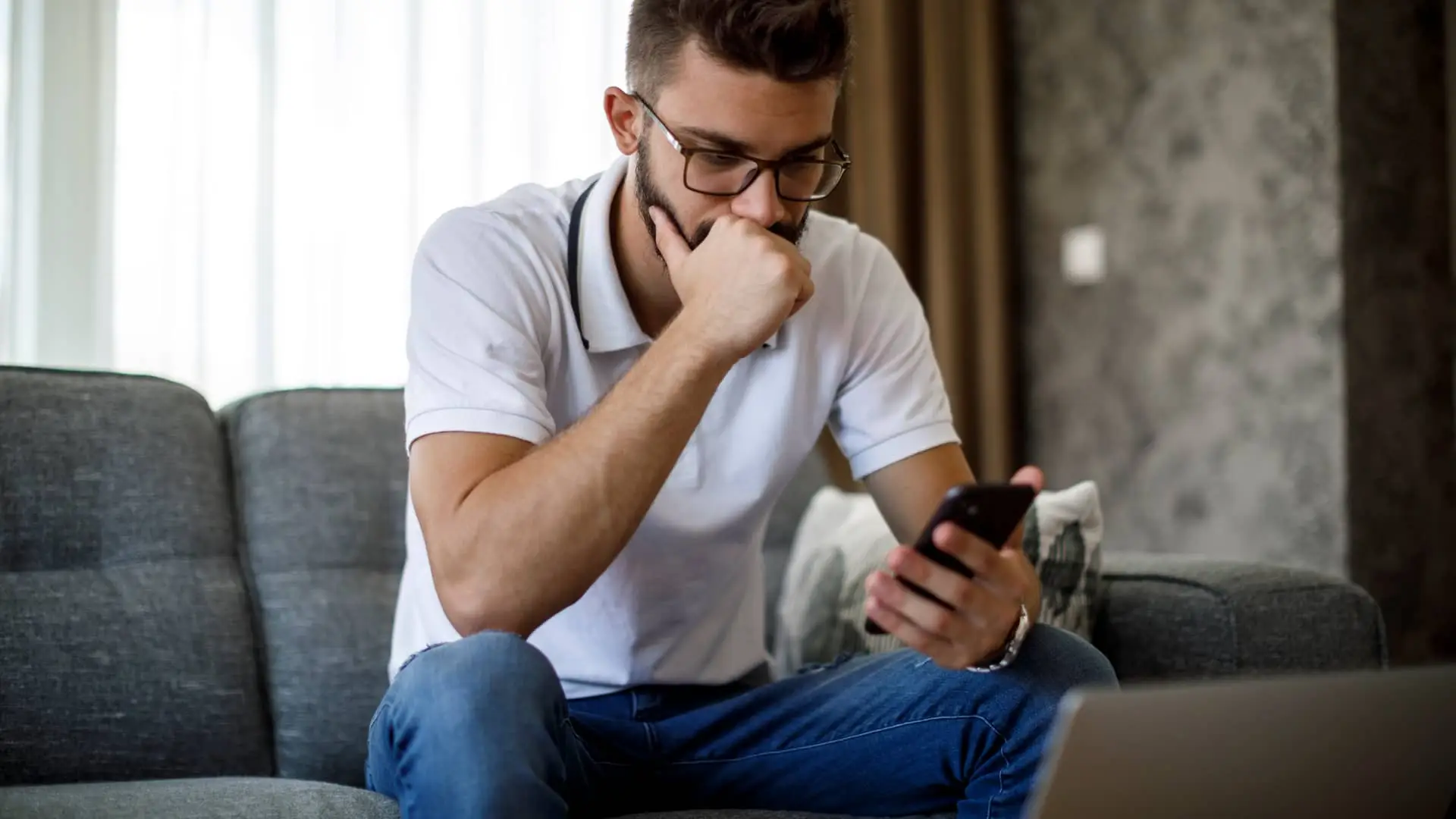 Joven desempleado viendo en su smartphone ofertas de trabajo Joven desempleado viendo en su smartphone ofertas de trabajo