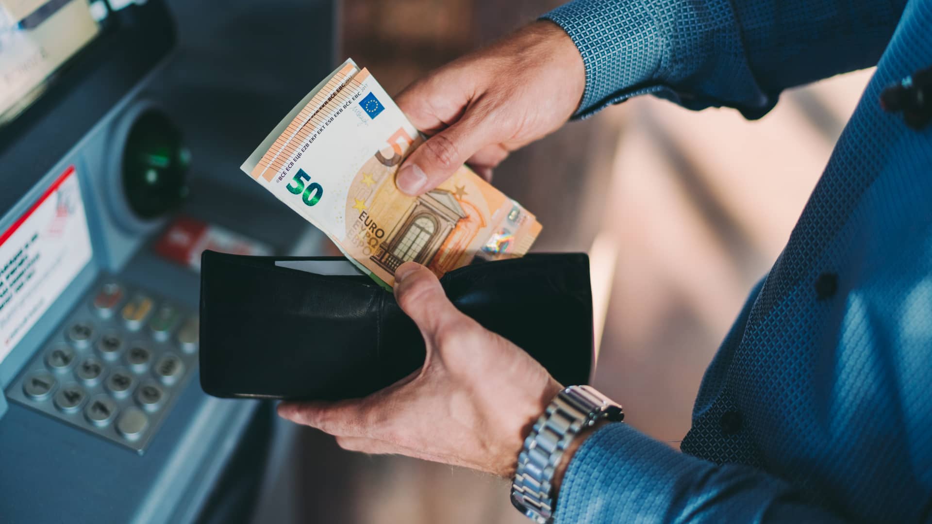 Hombre sacando dinero de cajero sin necesidad de tarjeta Hombre sacando dinero de cajero sin necesidad de tarjeta