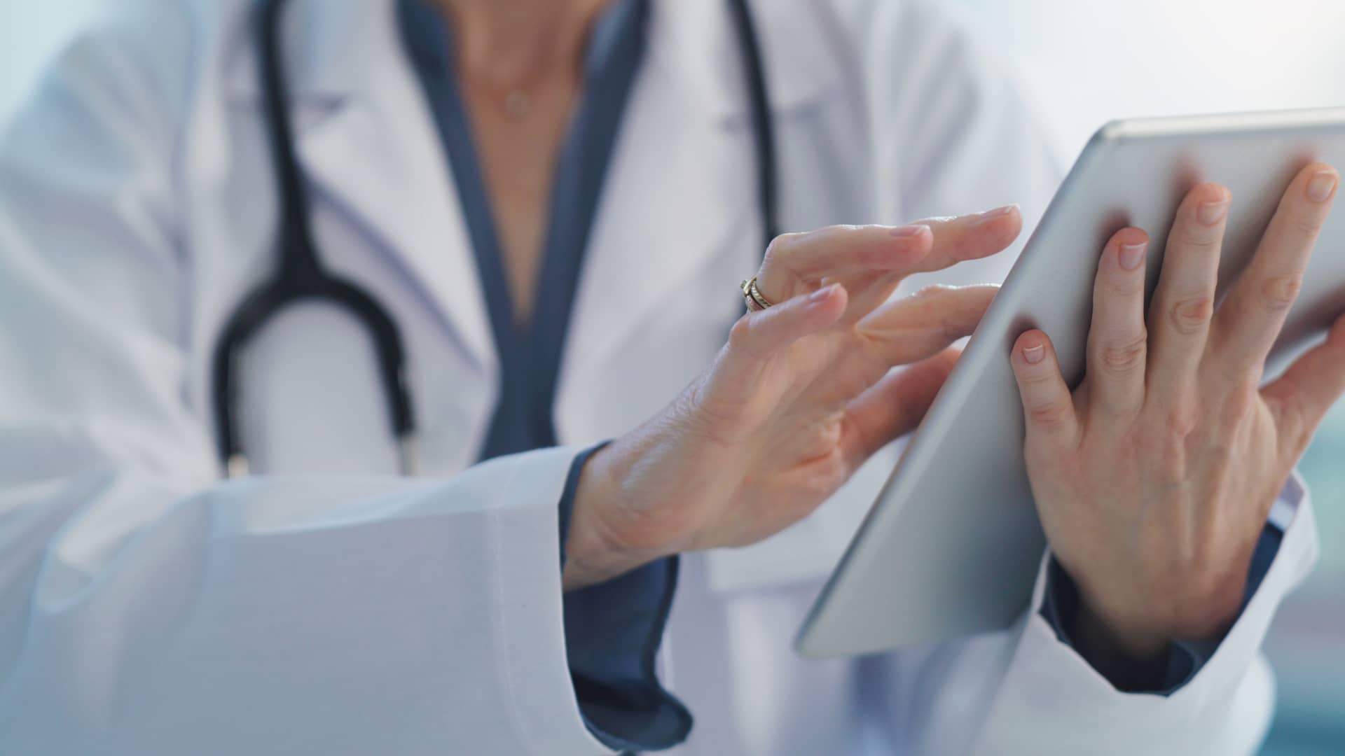 Médica especialista en andrología revisa los resultados de un paciente de seguros Adeslas en su tablet