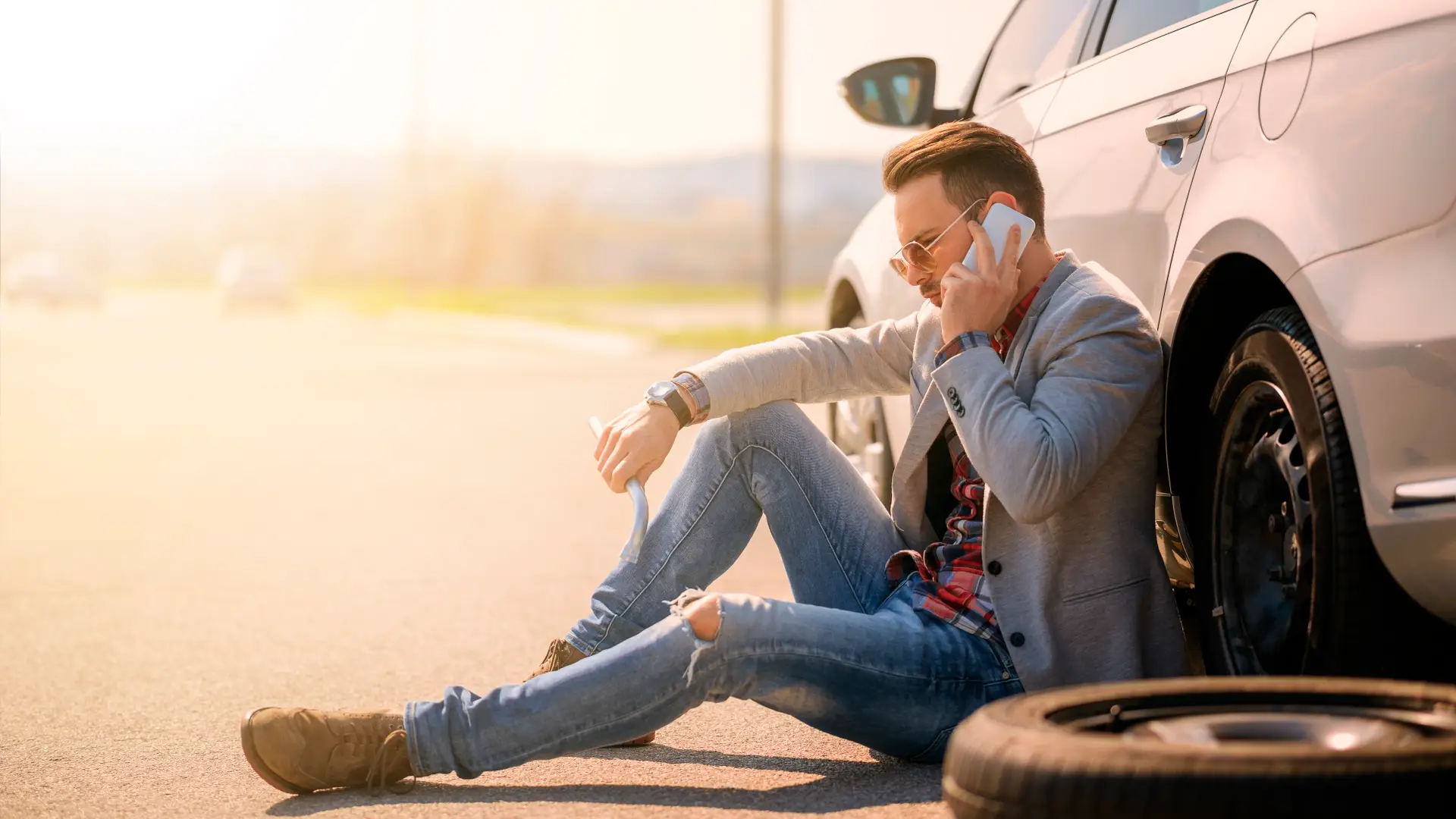 Hombre tirado en carretera por un pinchazo contactando con su seguro de coche adeslas para que le ayuden Hombre tirado en carretera por un pinchazo contactando con su seguro de coche adeslas para que le ayuden
