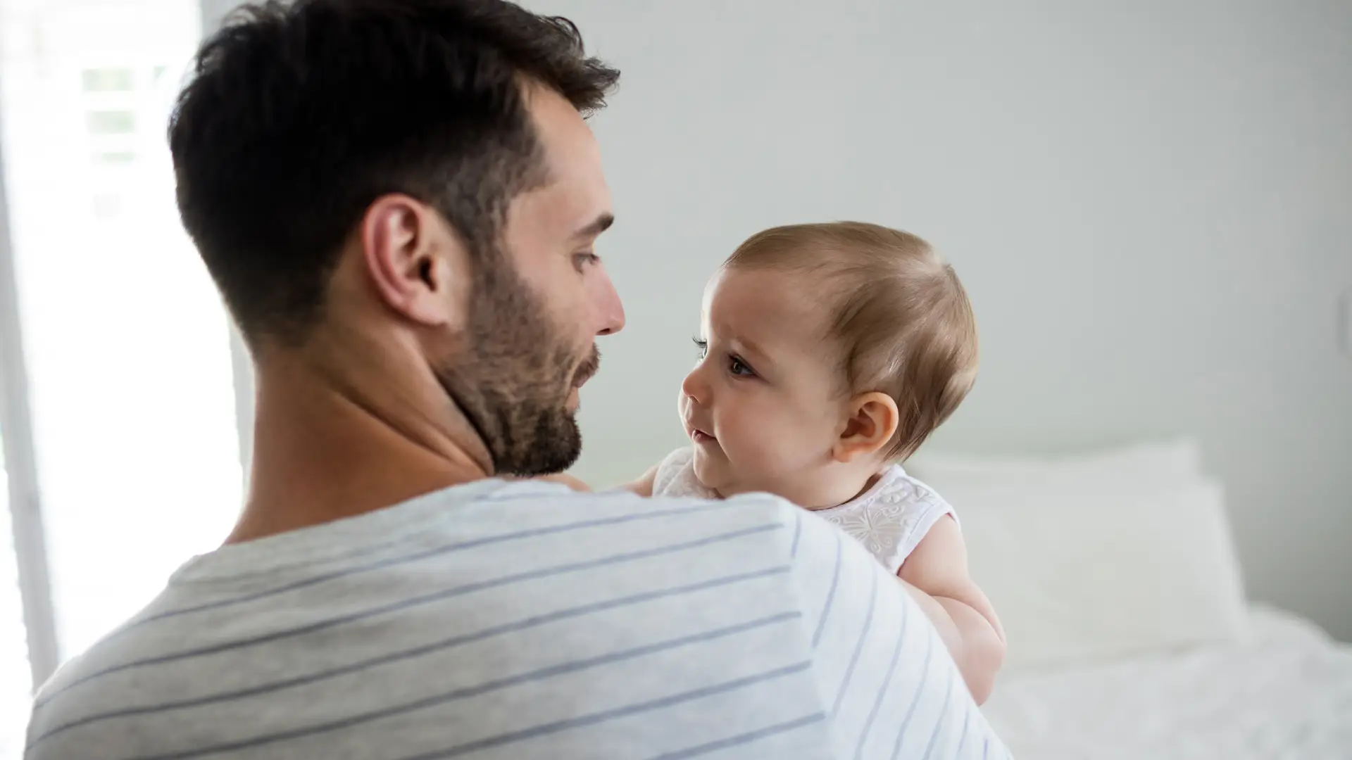 Padre mira embelesado a su bebé con la tranquilidad de haber contratado un seguro de vida Adeslas que asegure el futuro de su hijo Padre mira embelesado a su bebé con la tranquilidad de haber contratado un seguro de vida Adeslas que asegure el futuro de su hijo