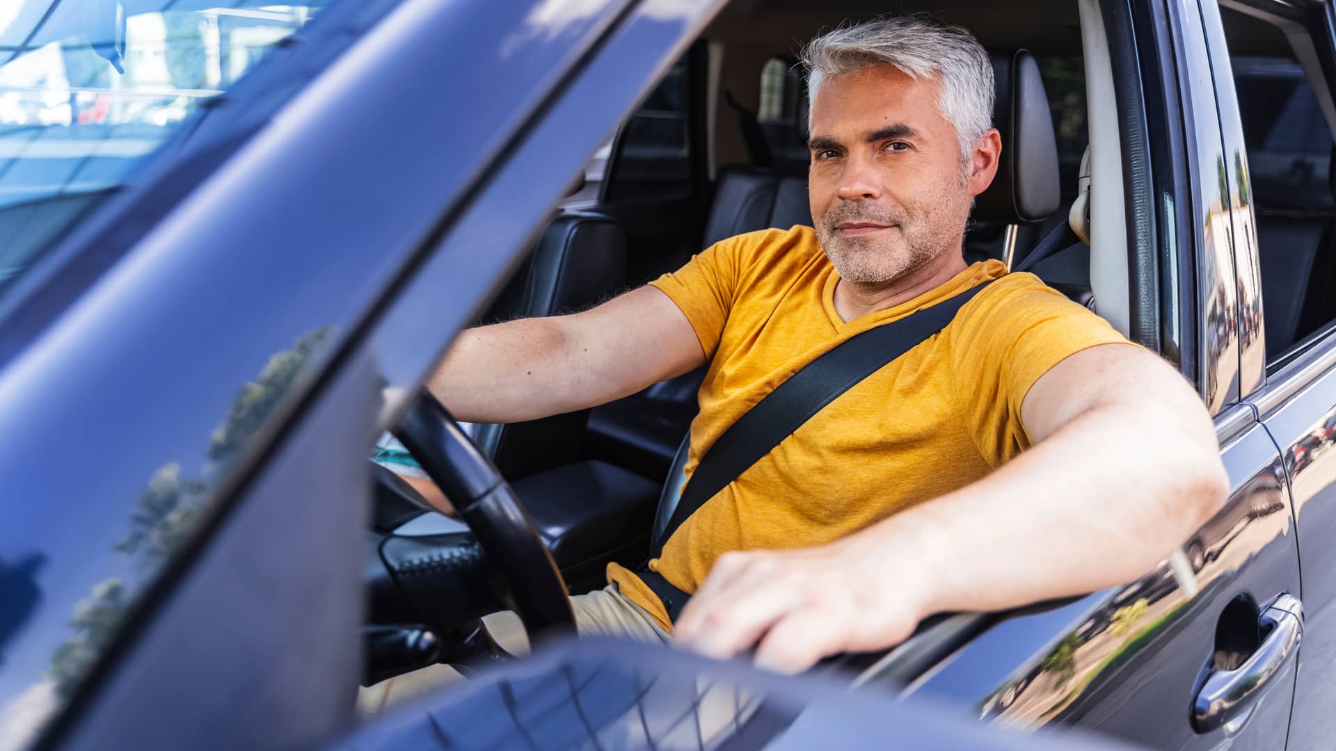 Hombre sonriente conduciendo su coche con seguro de allianz Hombre sonriente conduciendo su coche con seguro de allianz