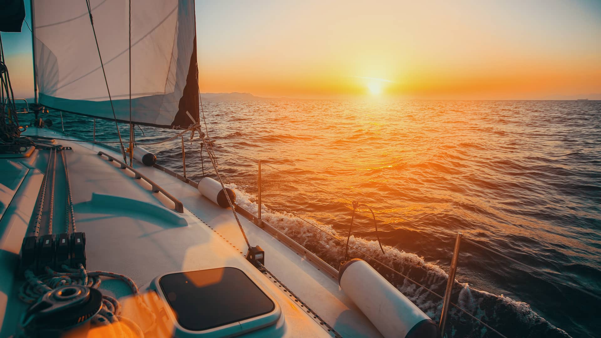 Barco de vela navegando en la puesta de sol con seguro para embarcaciones allianz