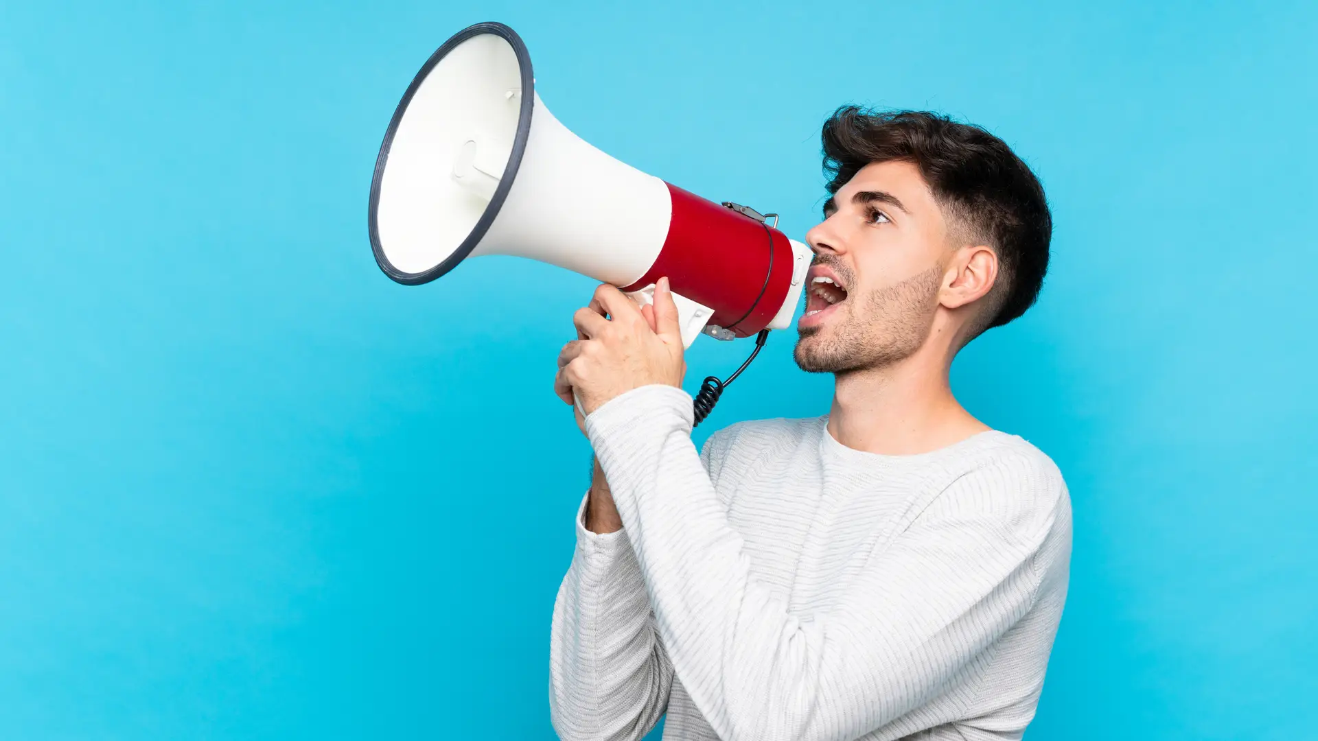Un joven con un megafono sobre un fondo azul que representa las opiniones de Ama Seguros
