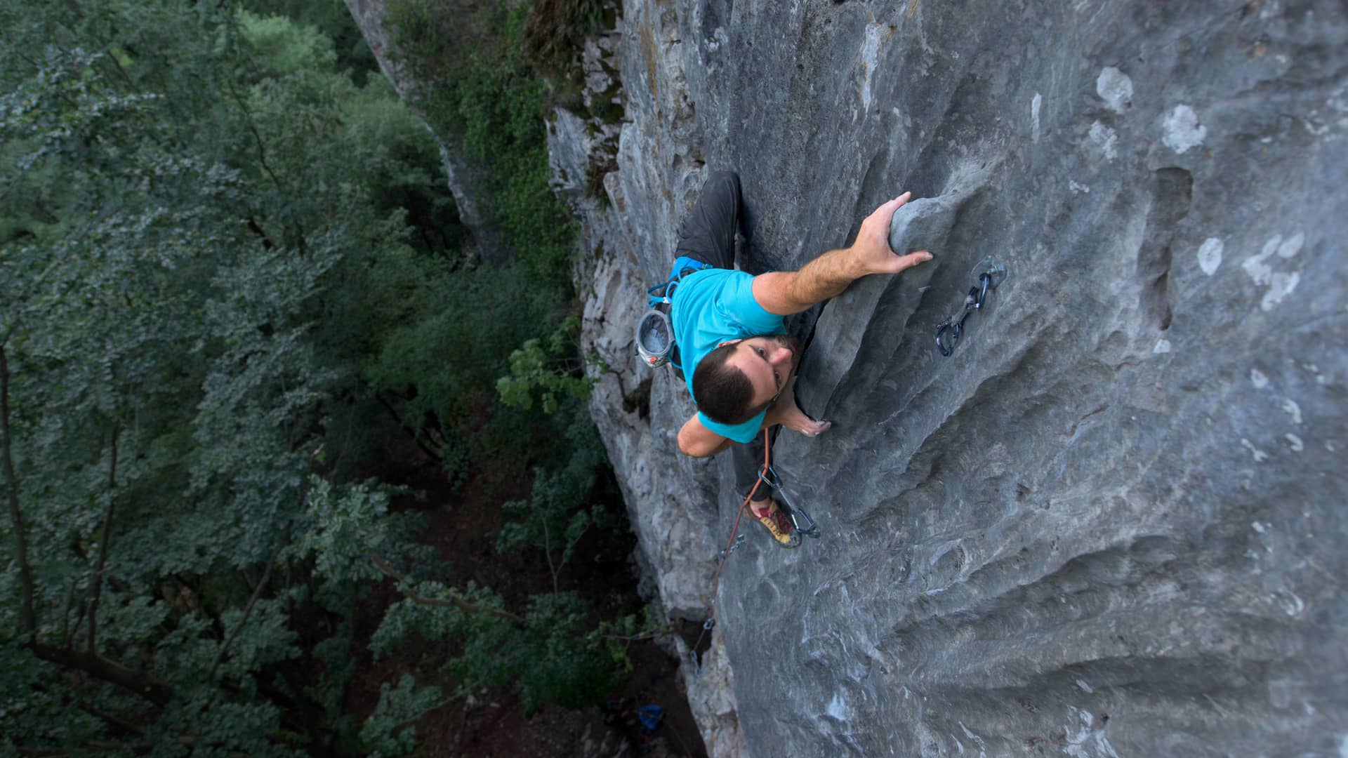 Joven con seguro de vida de asisa subiendo pared con agarres de una montaña