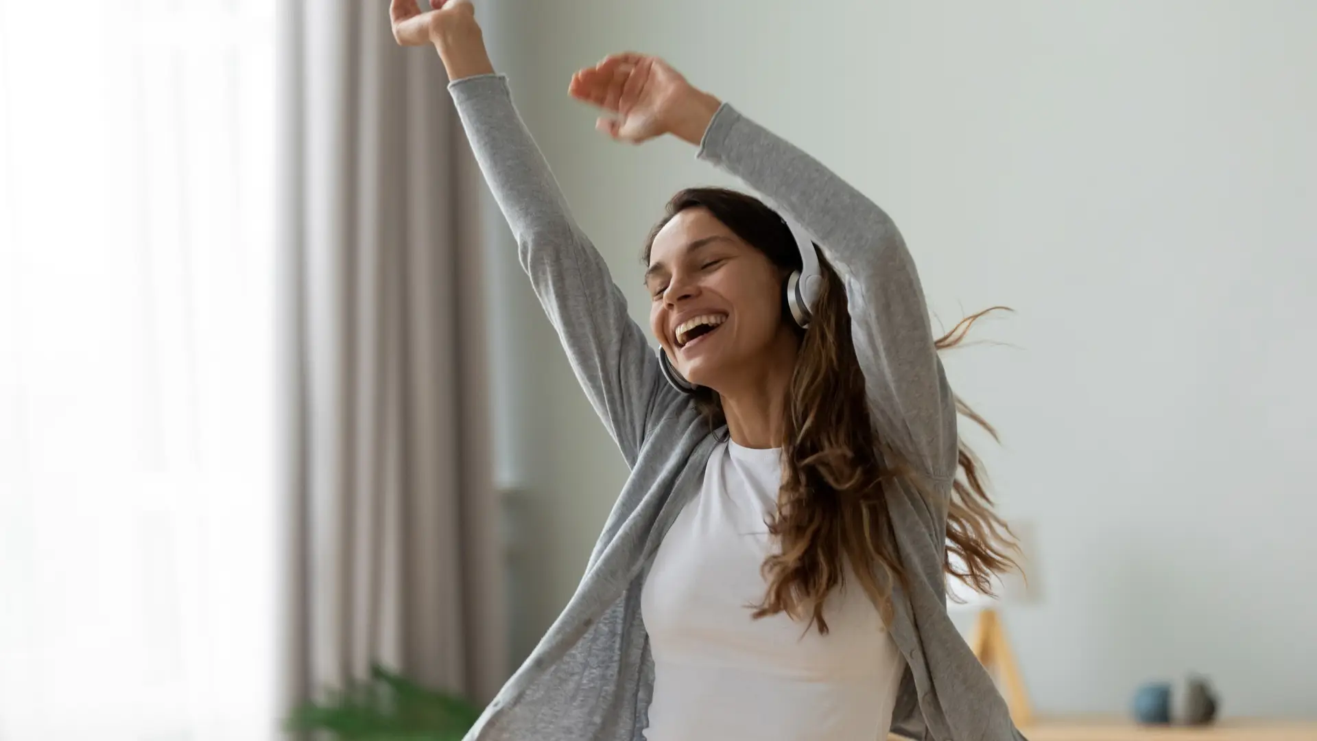 Mujer con seguro de hogar atlantis contratado bailando cantando y sonriendo en su casa