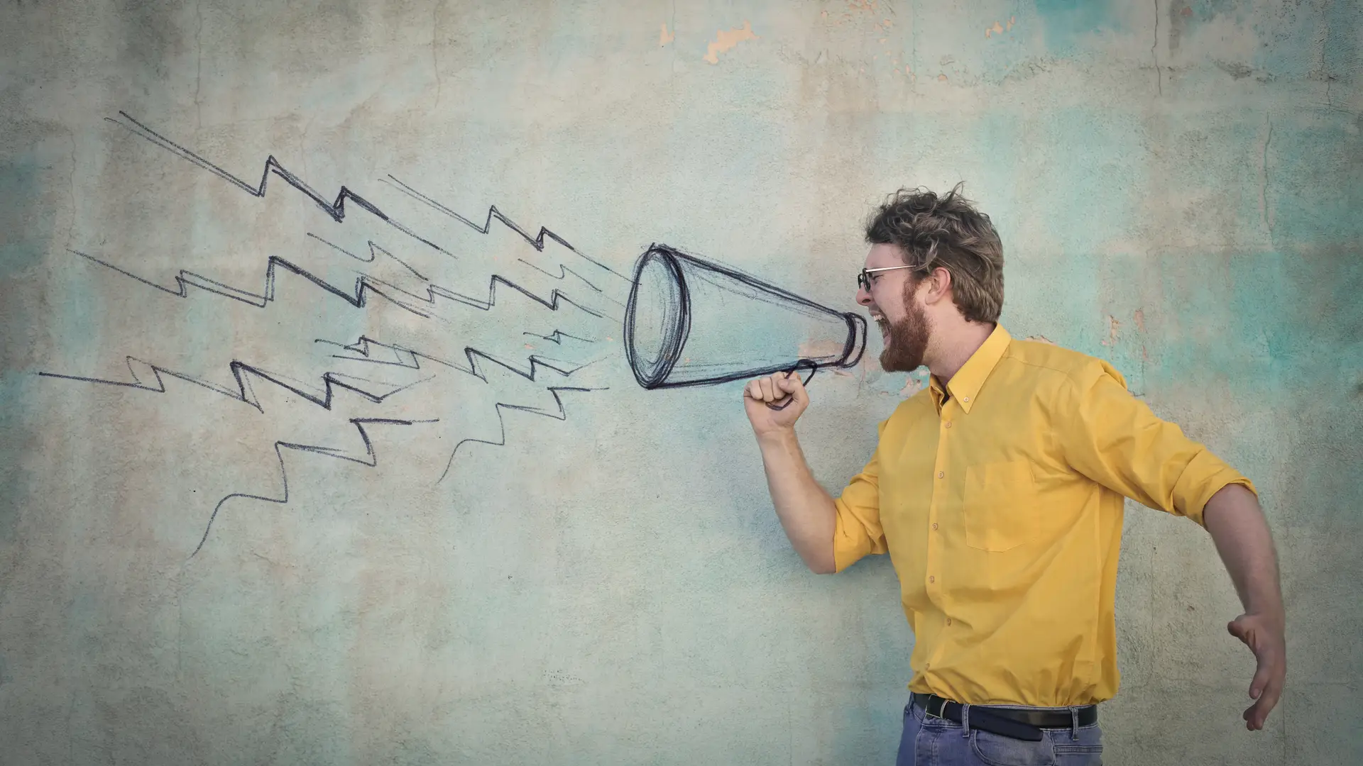 chico con un megafono pintado en la pared simulando las opiniones de la aseguradora aura seguros