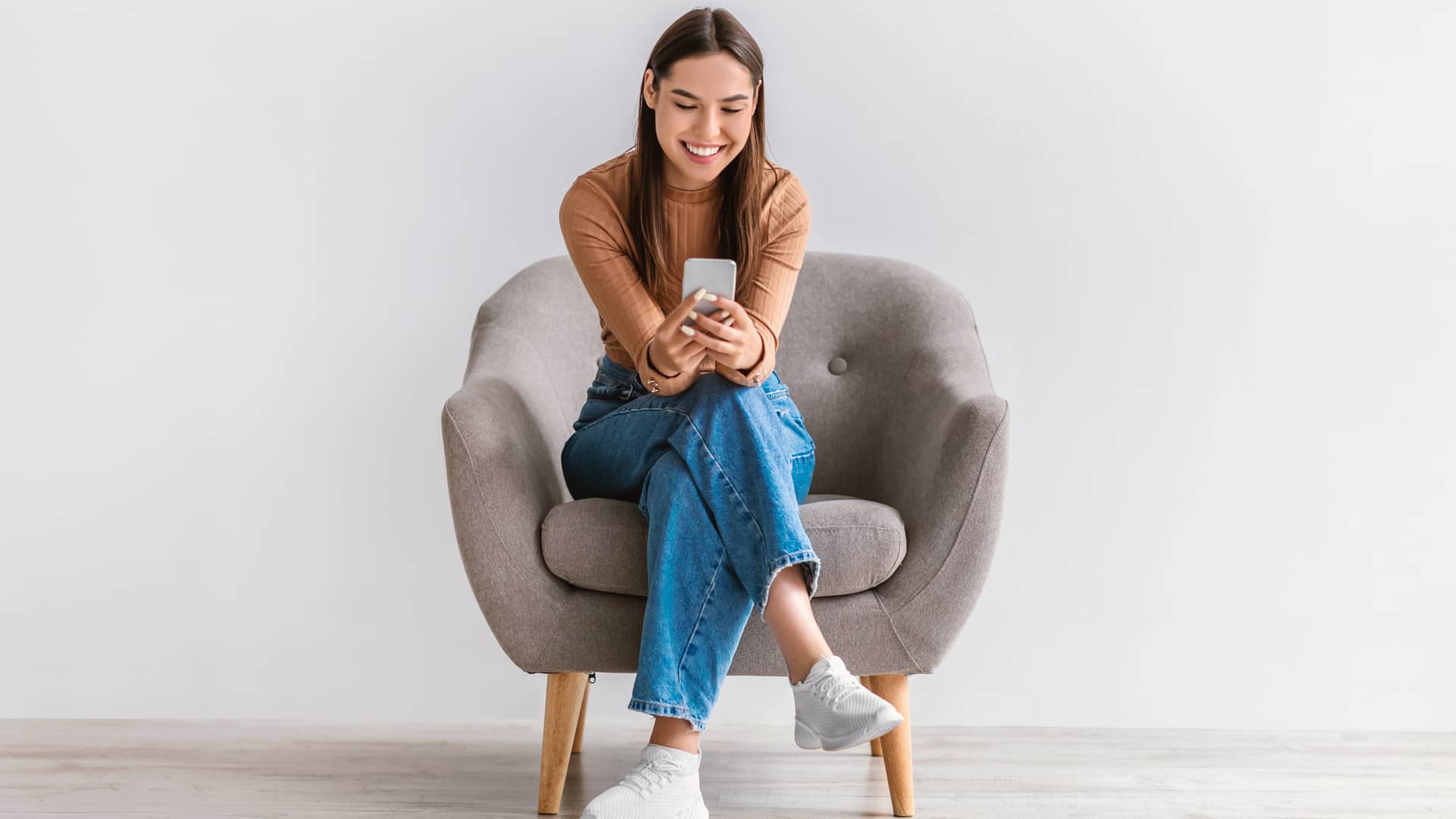 chica contenta con su movil despues de ver los descuentos de la empresa axa