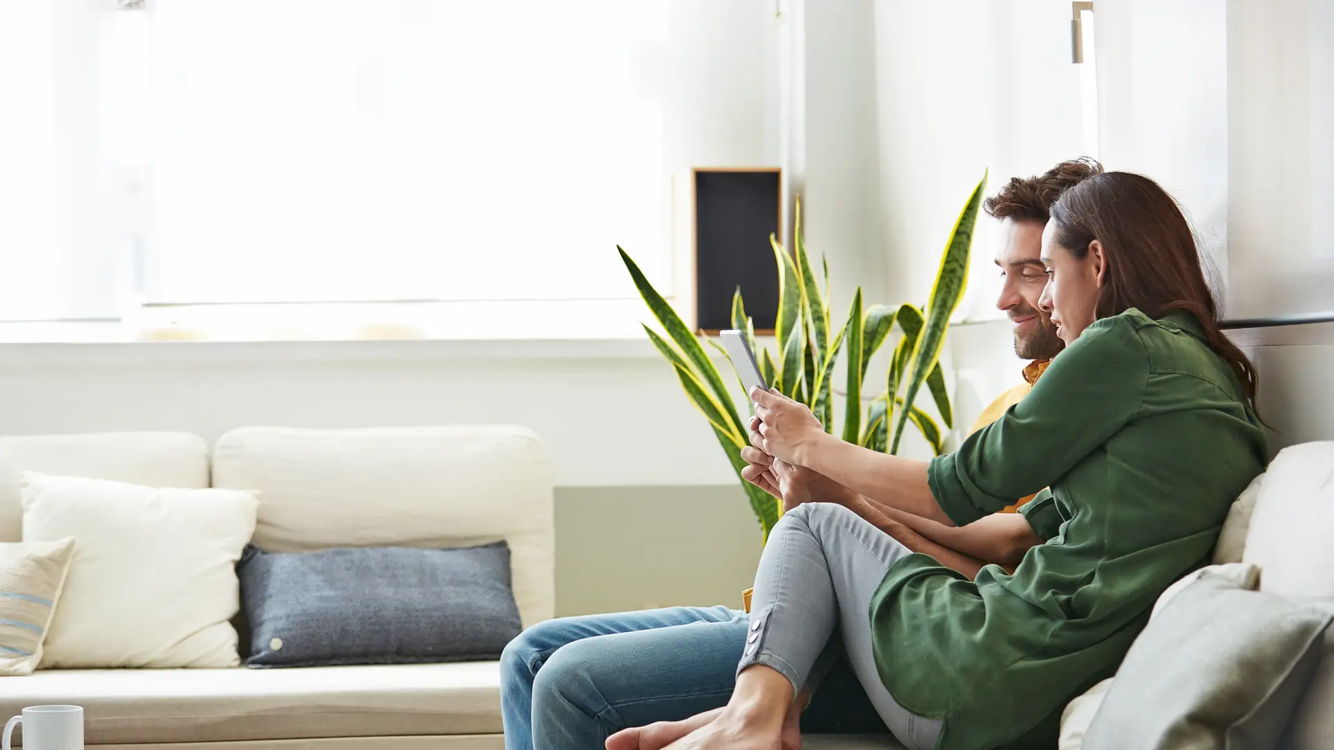 Pareja sentada en el sofá de su hogar con seguro de axa