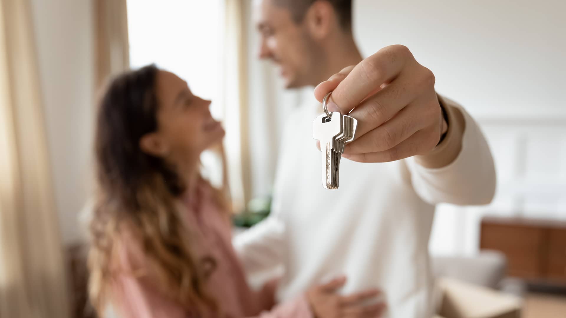 pareja presuminedo de las llaves de su nuevo piso con un seguro de arrendamiento de reale