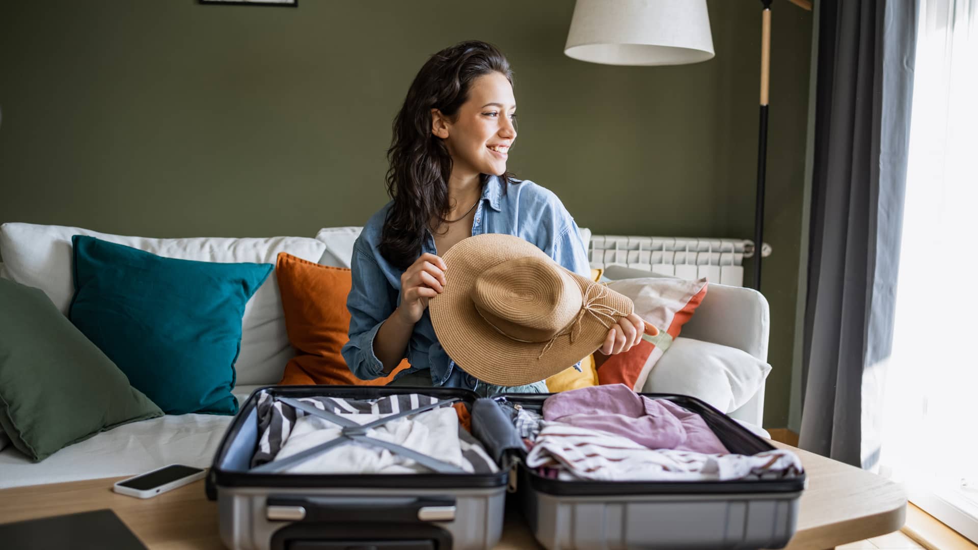 Mujer preparando su maleta para irse de vacaciones con seguro de viaje contratado con chapka Mujer preparando su maleta para irse de vacaciones con seguro de viaje contratado con chapka